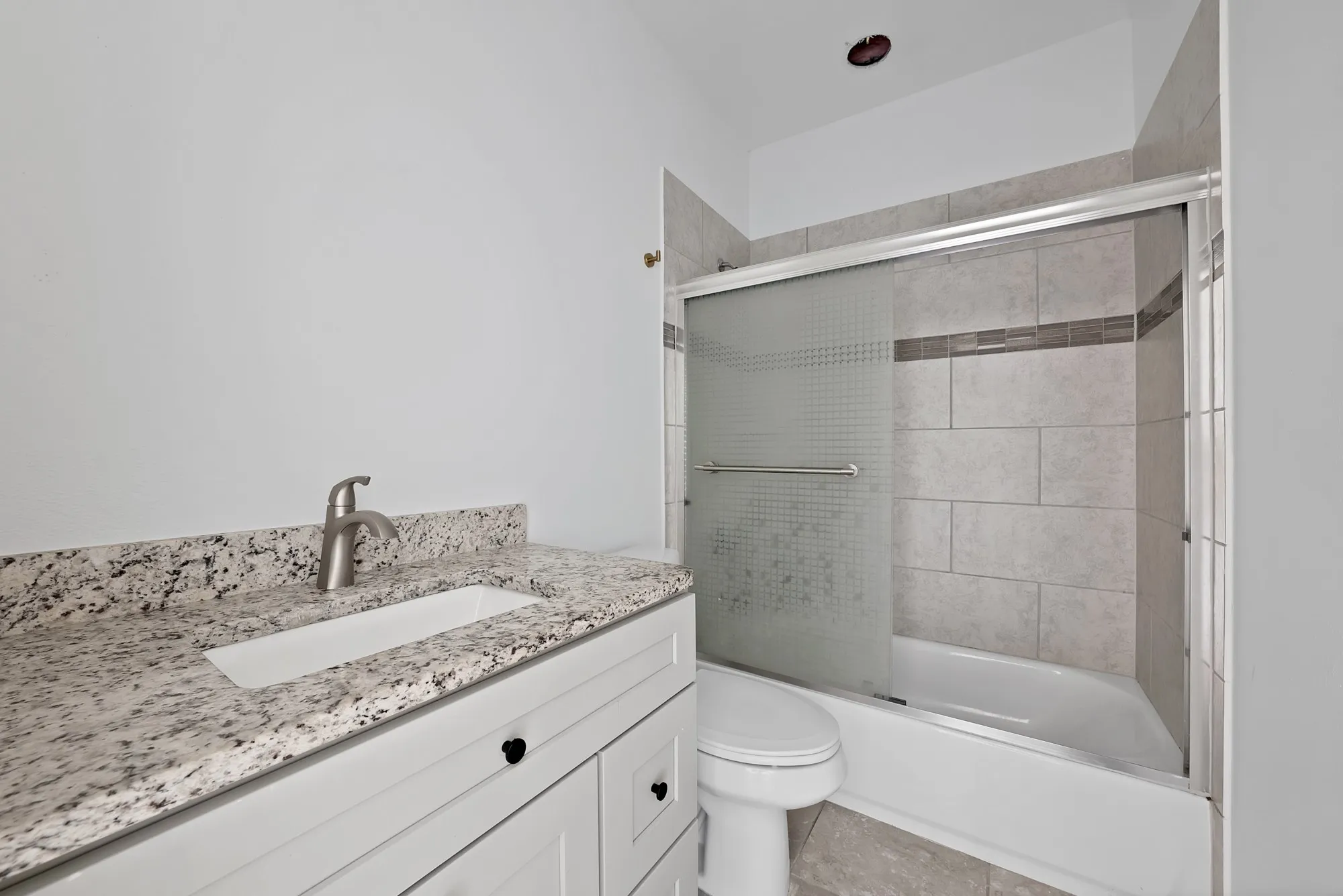 Modern bathroom featuring a white vanity with a light-colored speckled countertop, an undermount sink, and a brushed nickel faucet