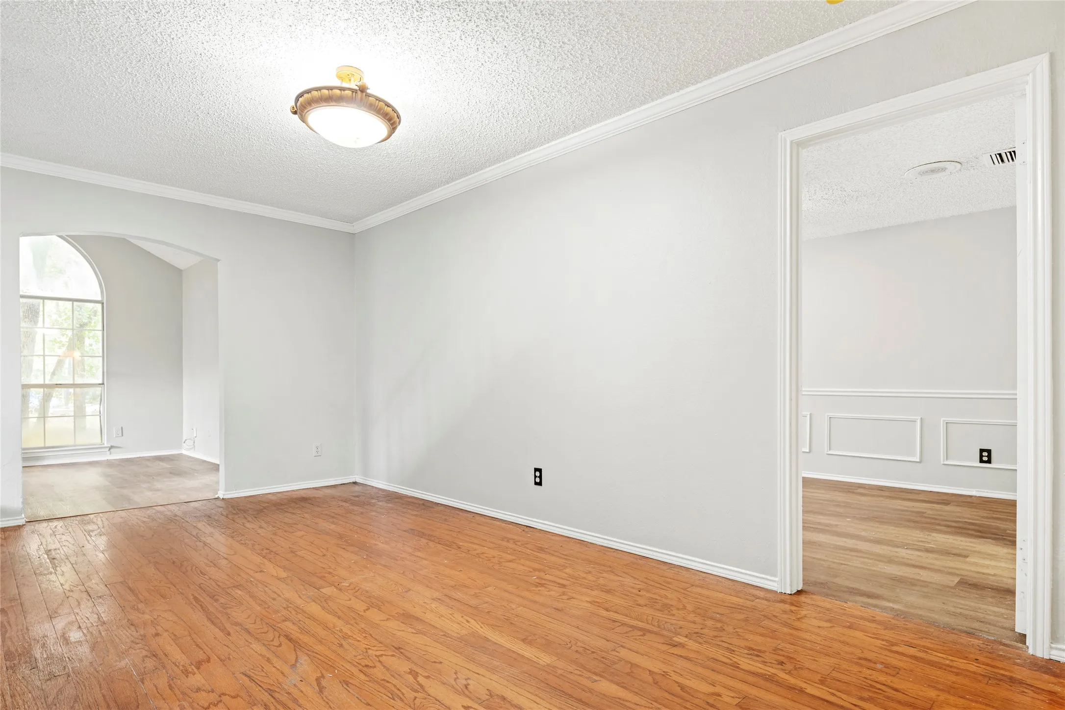 Interior room featuring wood-finish flooring, light gray walls, and crown molding