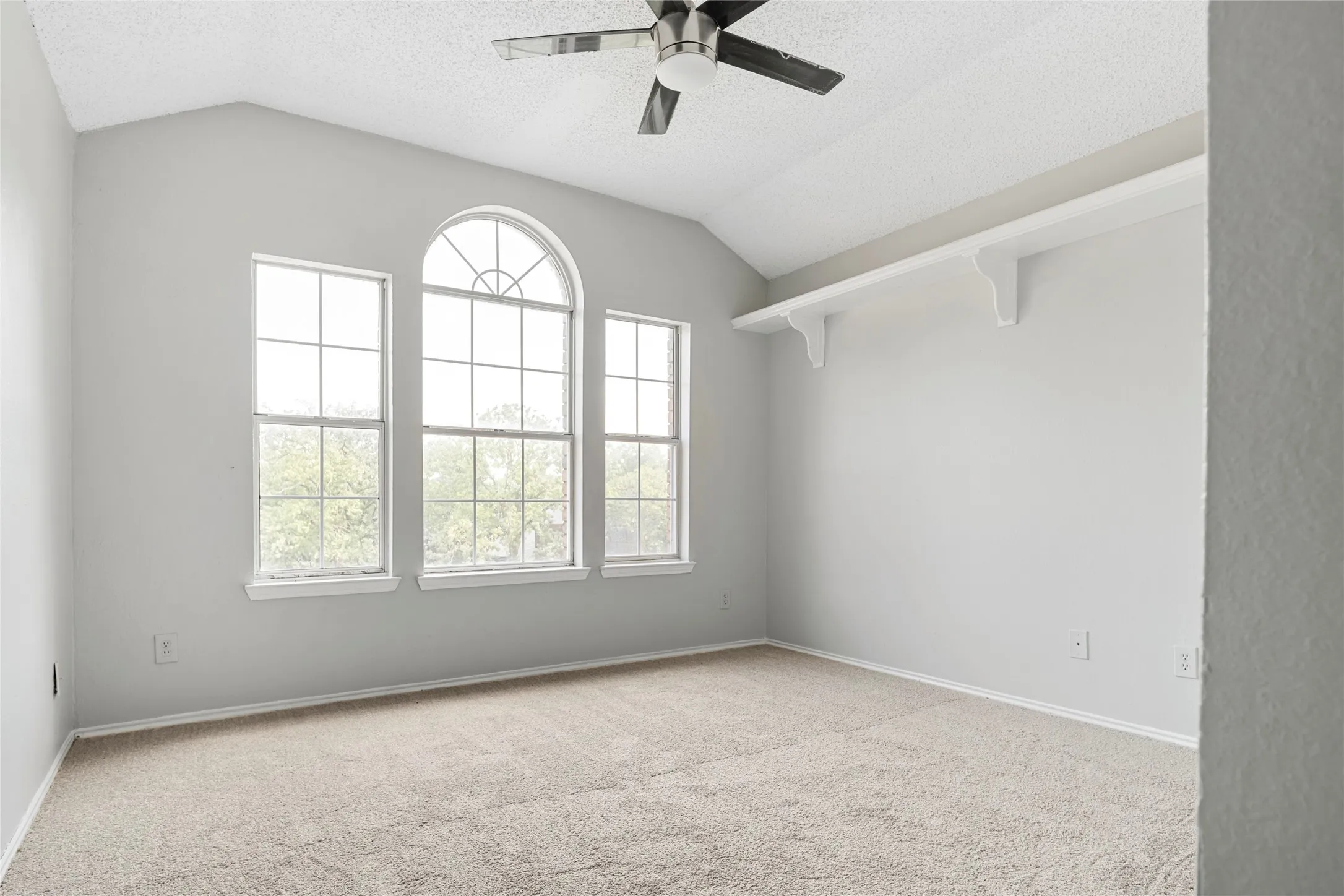 Spacious room featuring vaulted ceilings, a ceiling fan, and carpet flooring