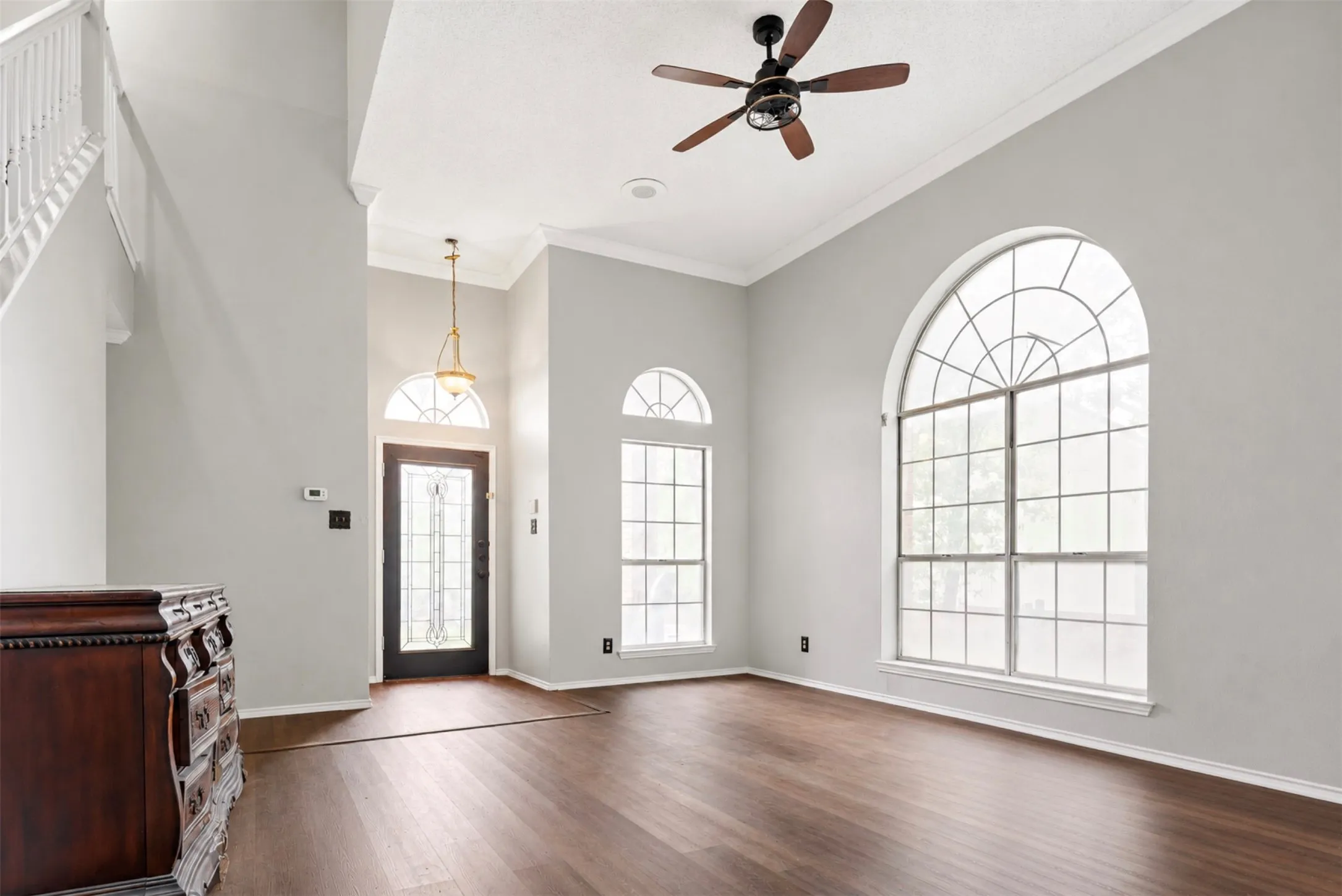 Spacious interior featuring wood-finish flooring, two-story ceilings, and a decorative ceiling fan