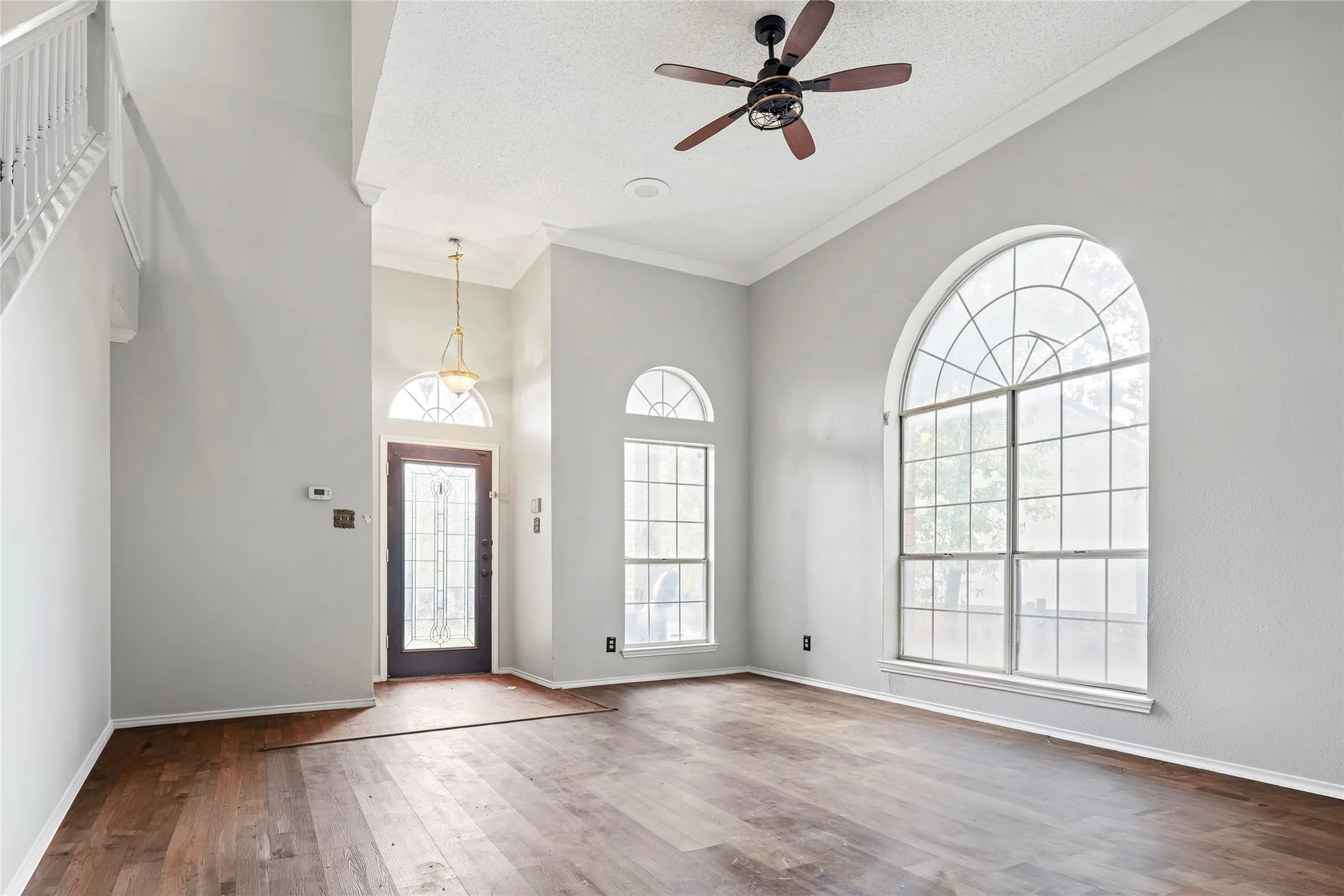 Spacious living area featuring high ceilings, wood-finish flooring, and multiple arched windows