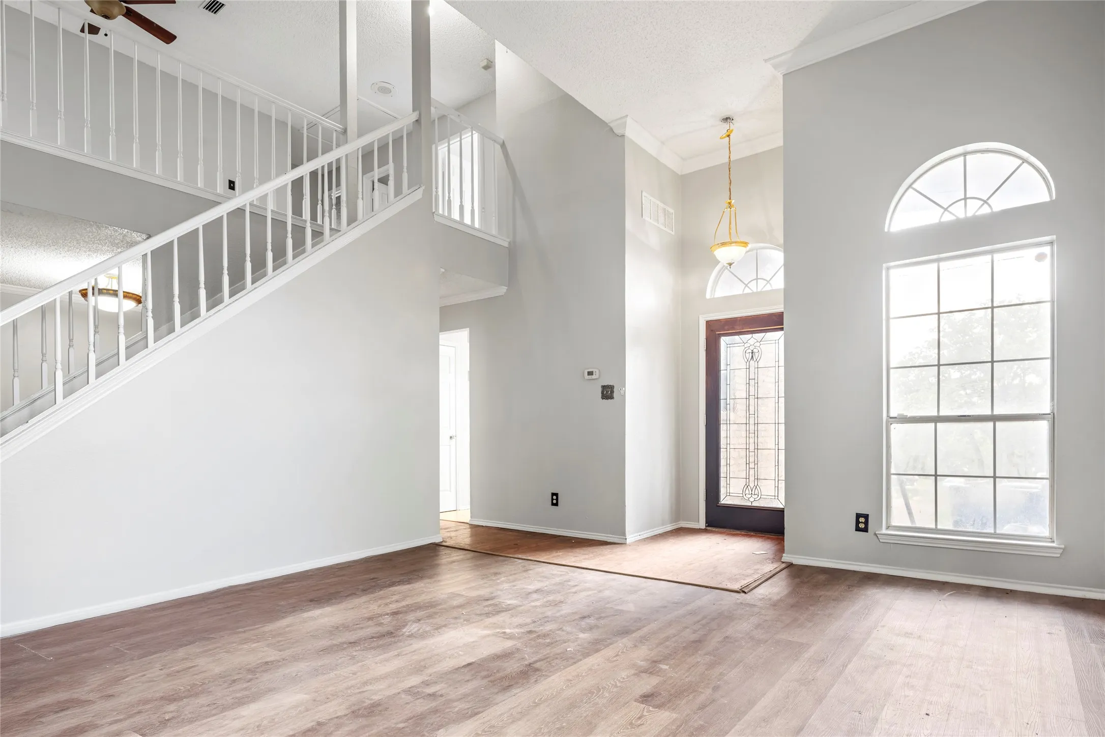 Vaulted entry featuring a leaded glass front door, transom window, and a prominent arched window