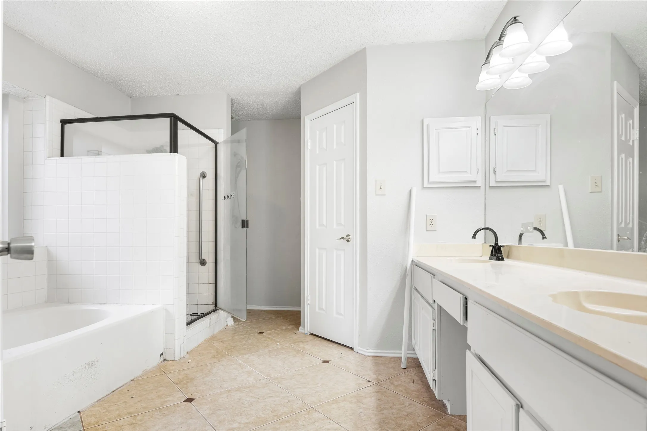 Spacious bathroom featuring a double vanity with integrated sinks, a wide mirror, and a five-light fixture