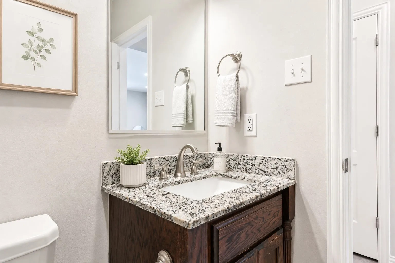 Bathroom vanity featuring a granite countertop, undermount sink, and brushed nickel faucet