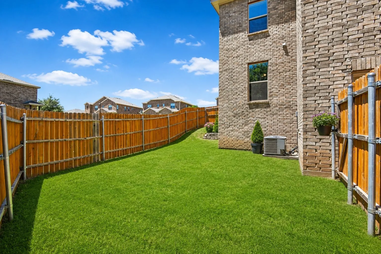 Expansive green lawn surrounded by a wooden privacy fence with metal posts