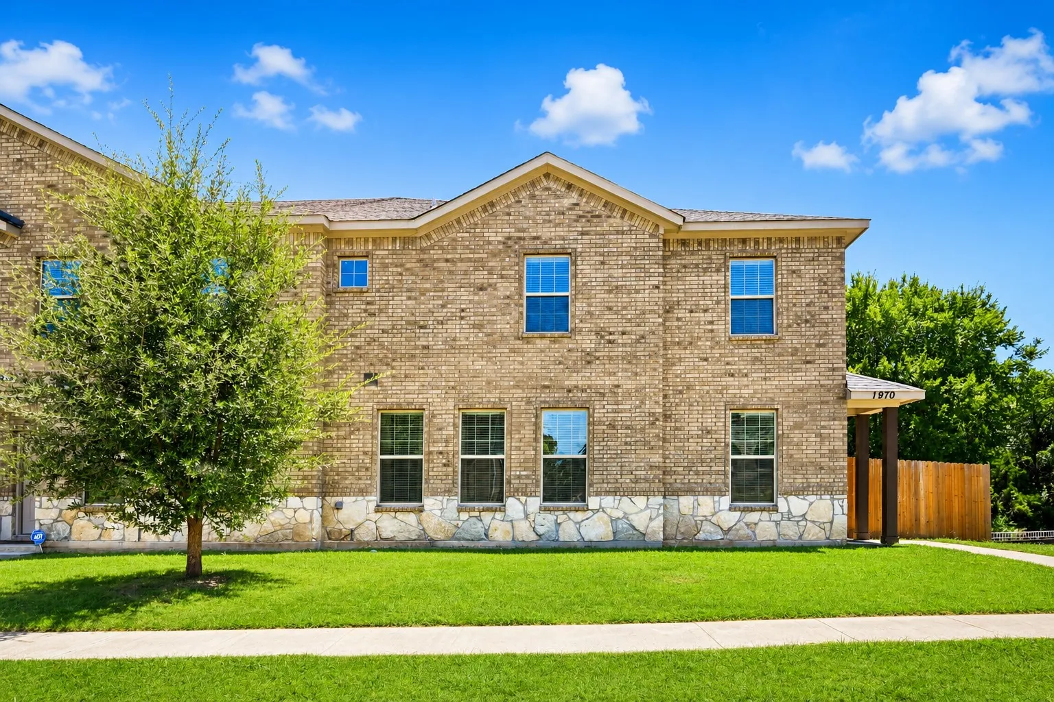 Two-story brick exterior with stone accents and multiple windows