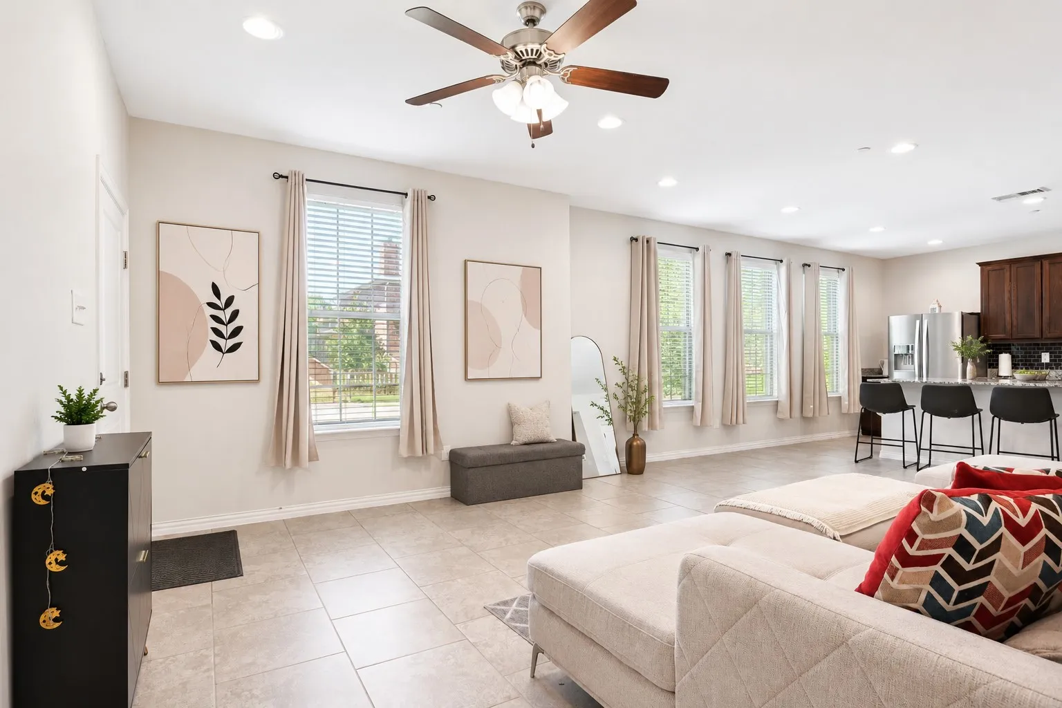 Open-concept living space with tile flooring throughout, multiple windows, and recessed lighting