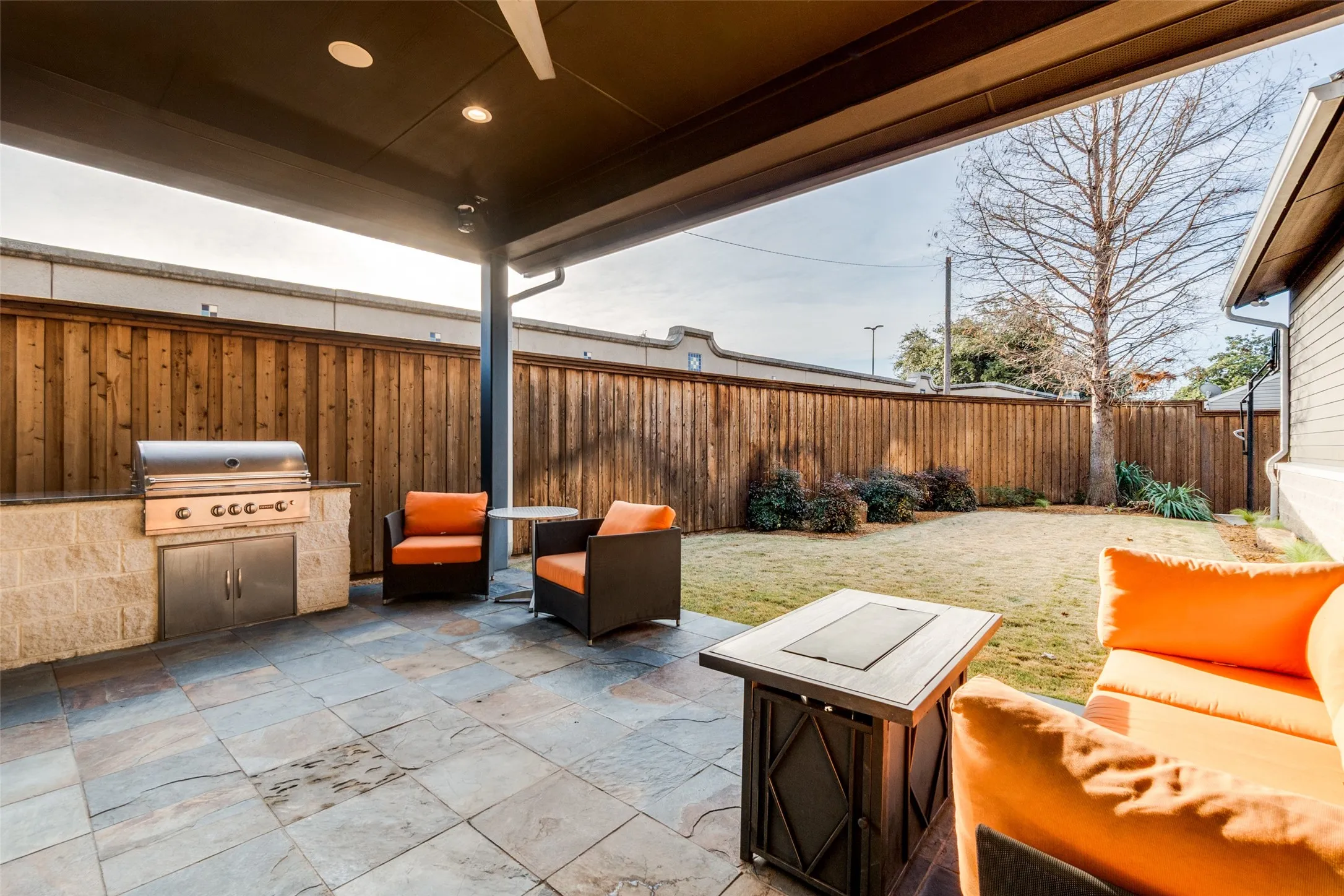 Covered outdoor patio featuring stone tile flooring and a built-in grill station with stainless steel appliances