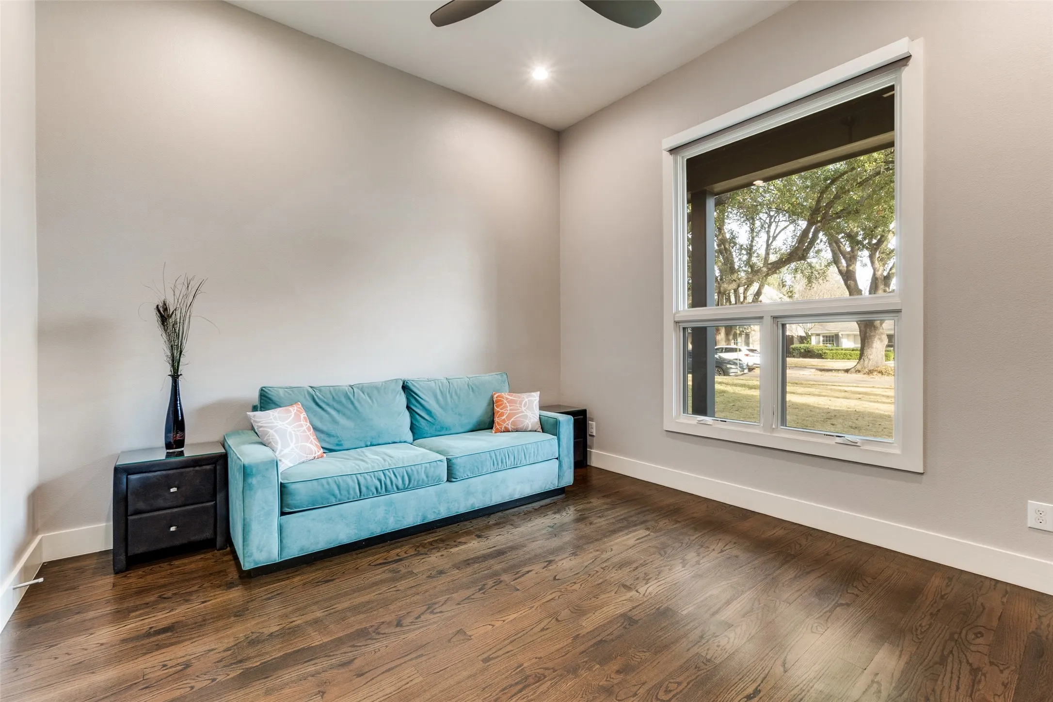 Hardwood flooring in downstairs bedroom  featuring a large window, vaulted ceiling, and recessed lighting