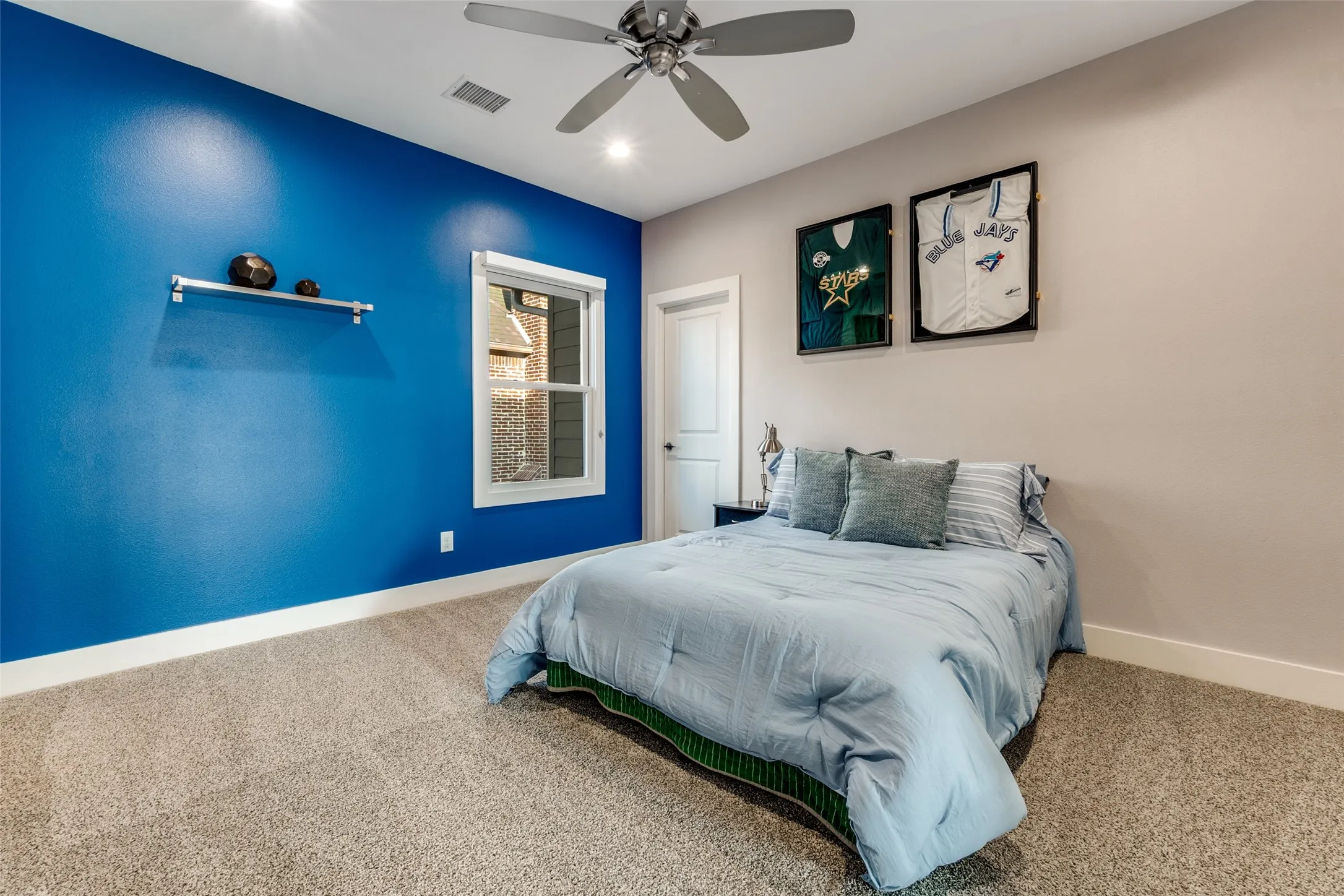 Carpeted kid's room featuring a white single-hung window, a ceiling fan with integrated lighting, and a built-in wall​​‌​​​​‌​​‌‌​‌‌​​​‌‌​‌​‌​‌​​​‌​​ shelf