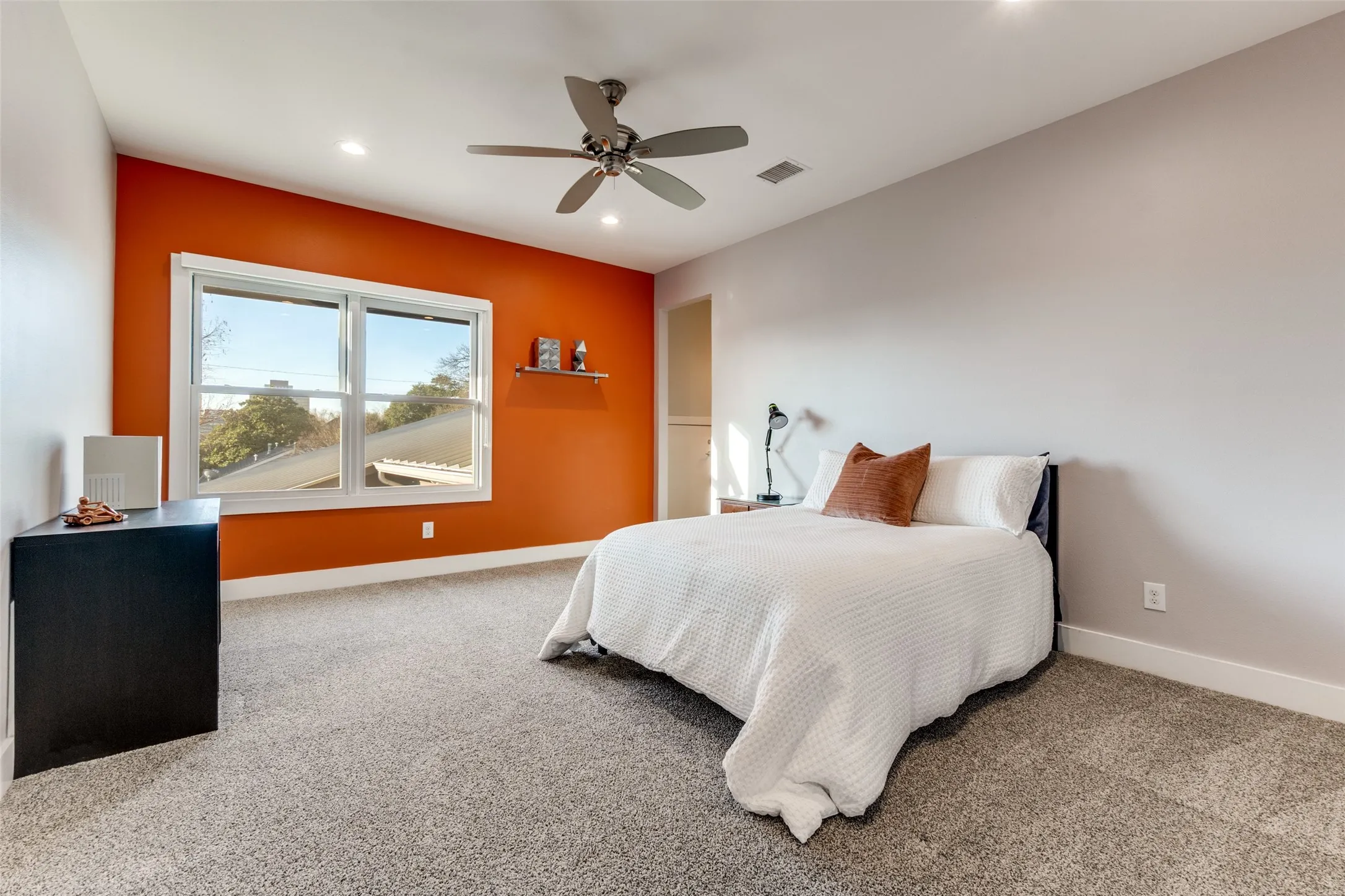 Spacious kid's room featuring a bright accent wall, large window, recessed lighting, ceiling fan, and carpet flooring