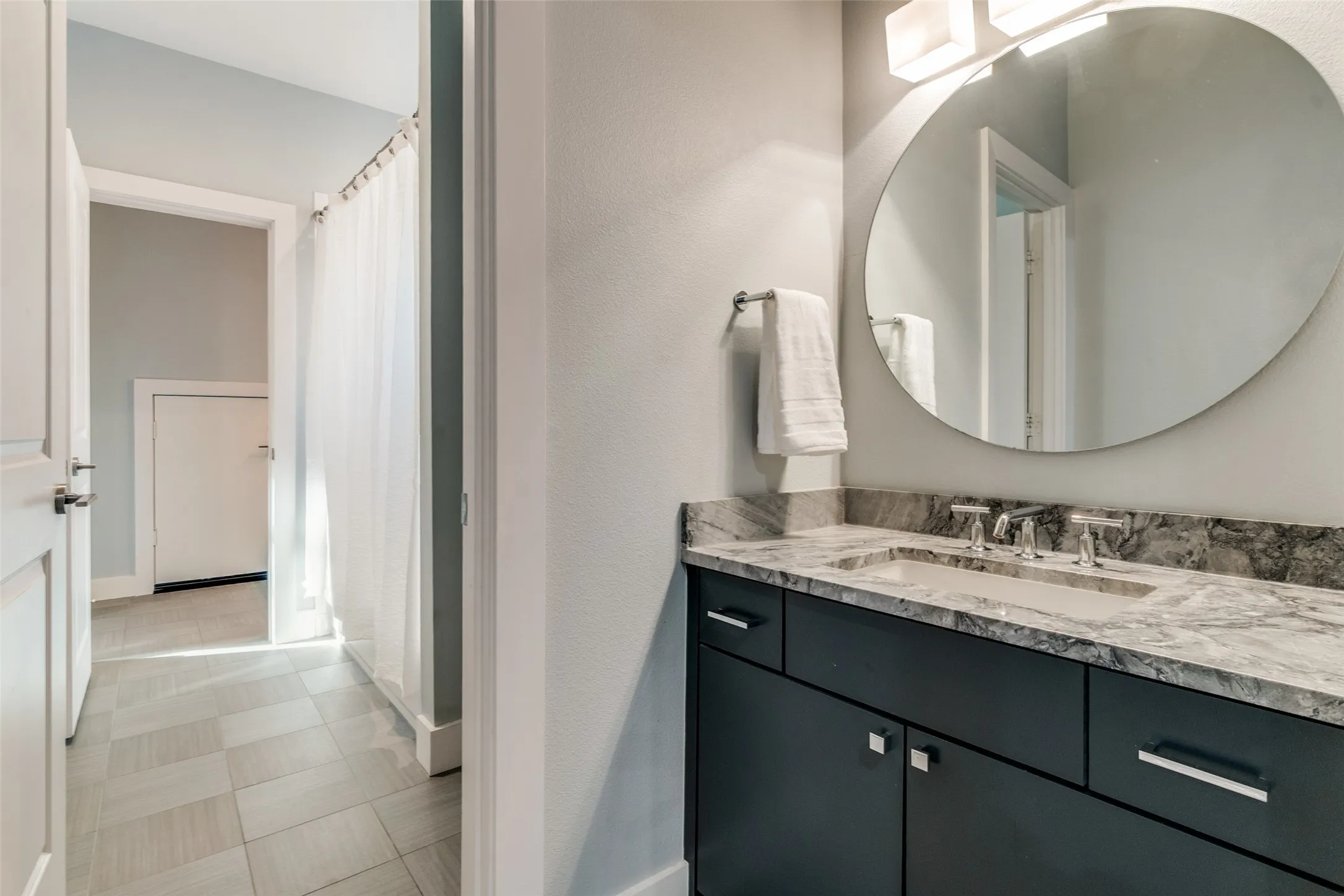 Bathroom vanity featuring a vessel sink with chrome fixtures, a stone-finish countertop, and dark cabinetry with rectangular hardware