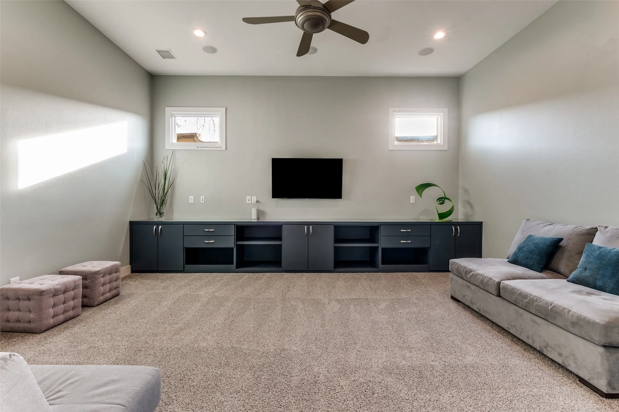 Spacious playroom featuring a built-in media console with storage, recessed lighting, and ceiling fan