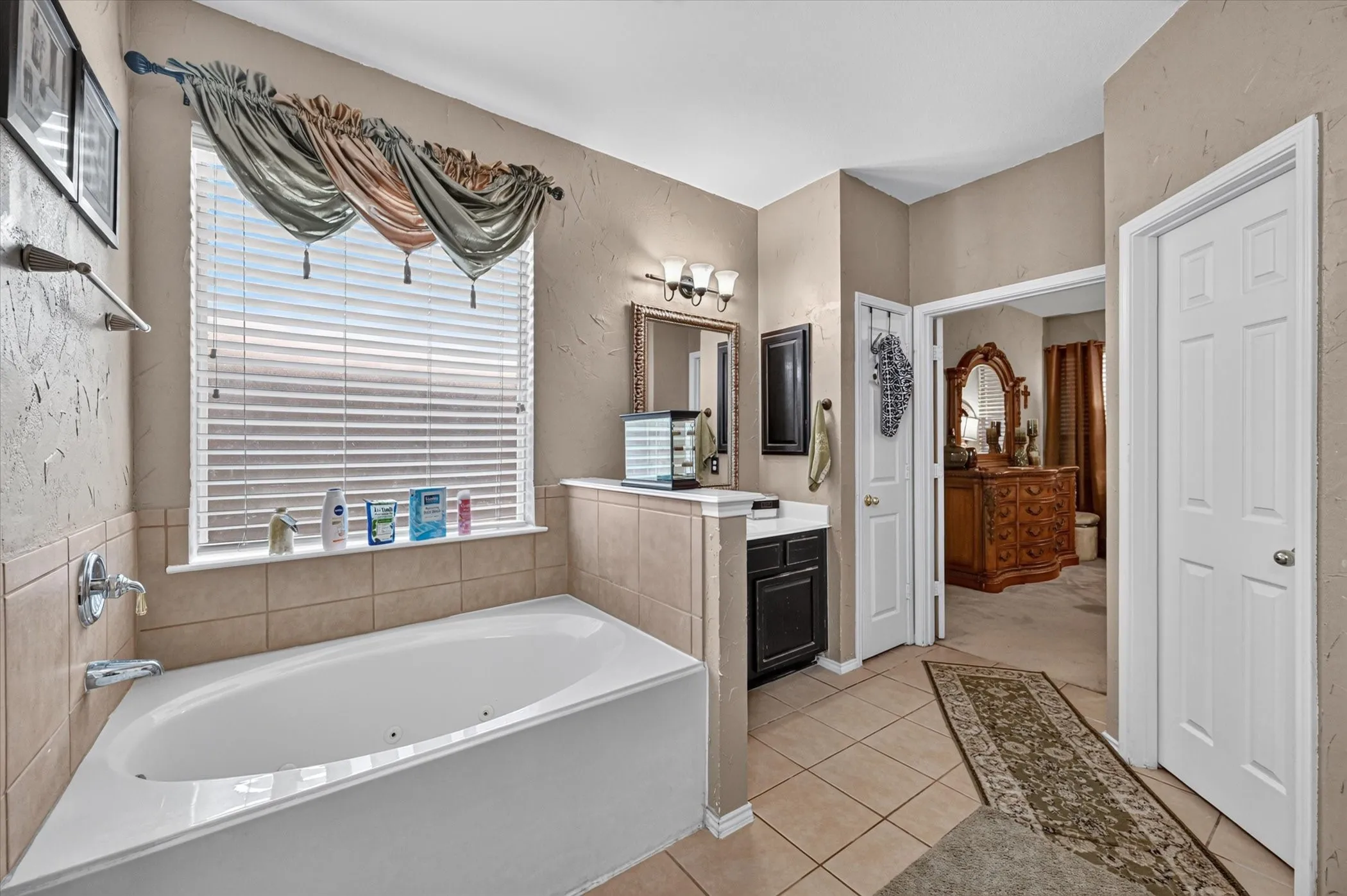 Soaking tub with tile surround and window featuring horizontal blinds