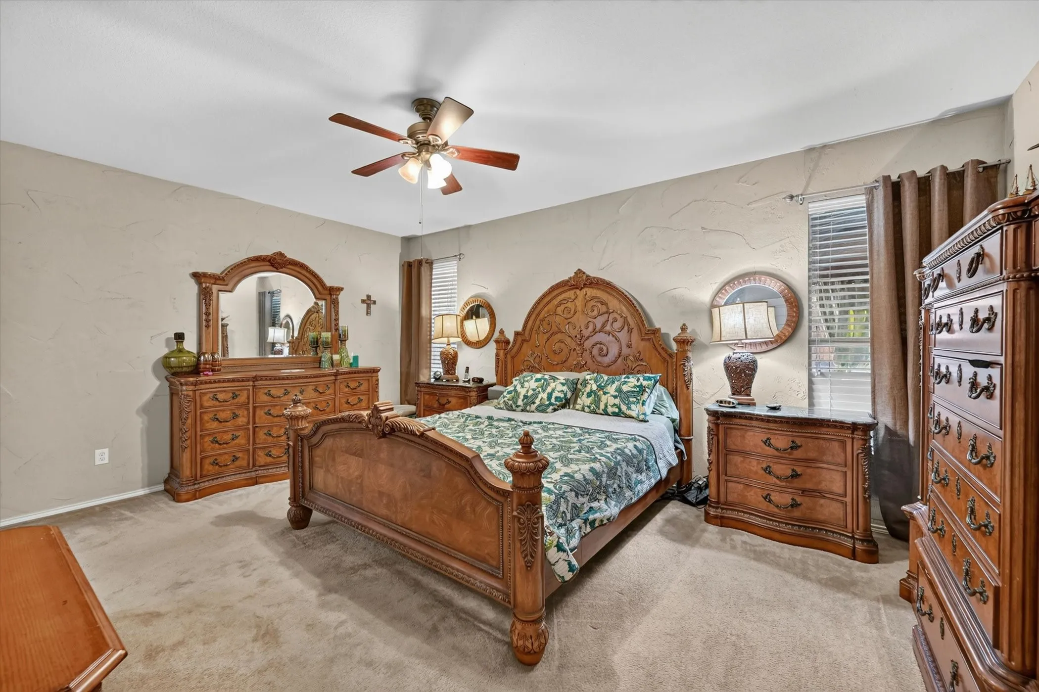 Spacious bedroom featuring light-colored carpet, textured wall finishes, and a ceiling fan with integrated lighting