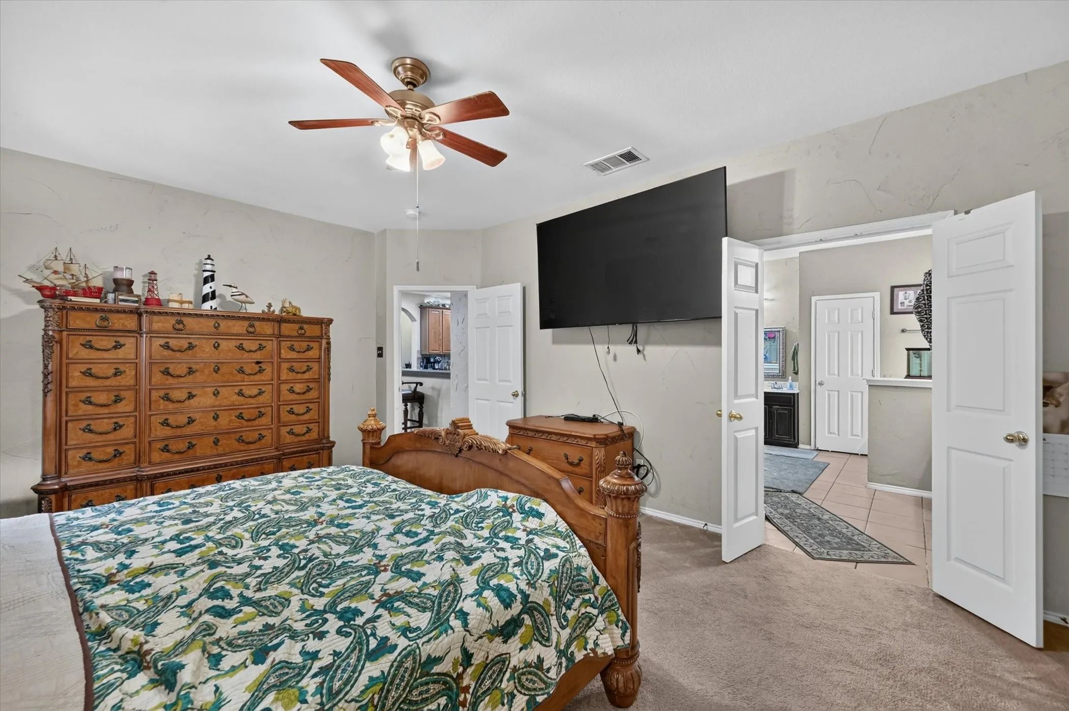 Carpeted room with a ceiling fan featuring a light fixture, neutral wall finishes, and a wide entryway with double doors