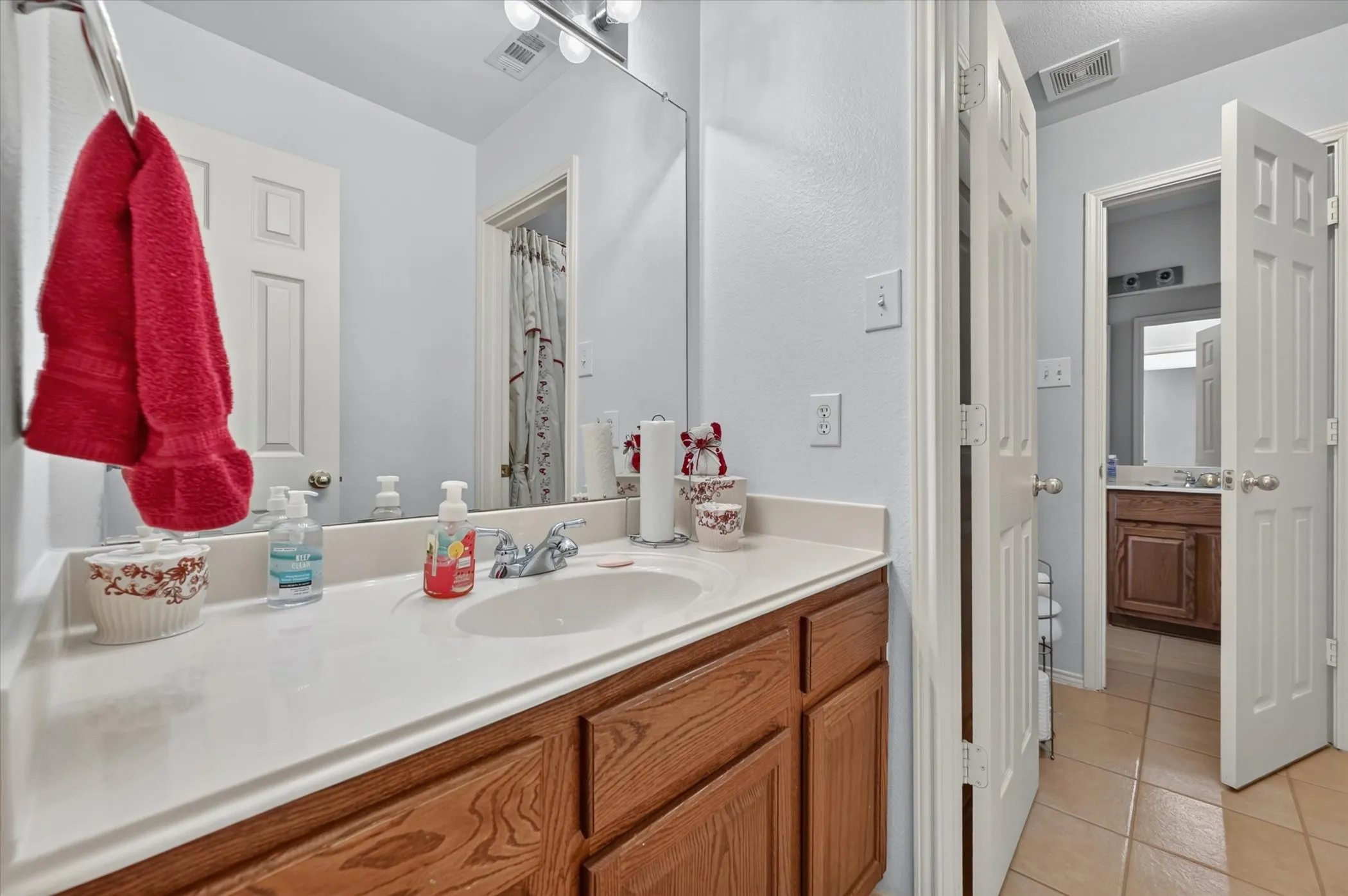 Bathroom vanity featuring a wood-finish cabinet, integrated sink, and a large wall-mounted mirror