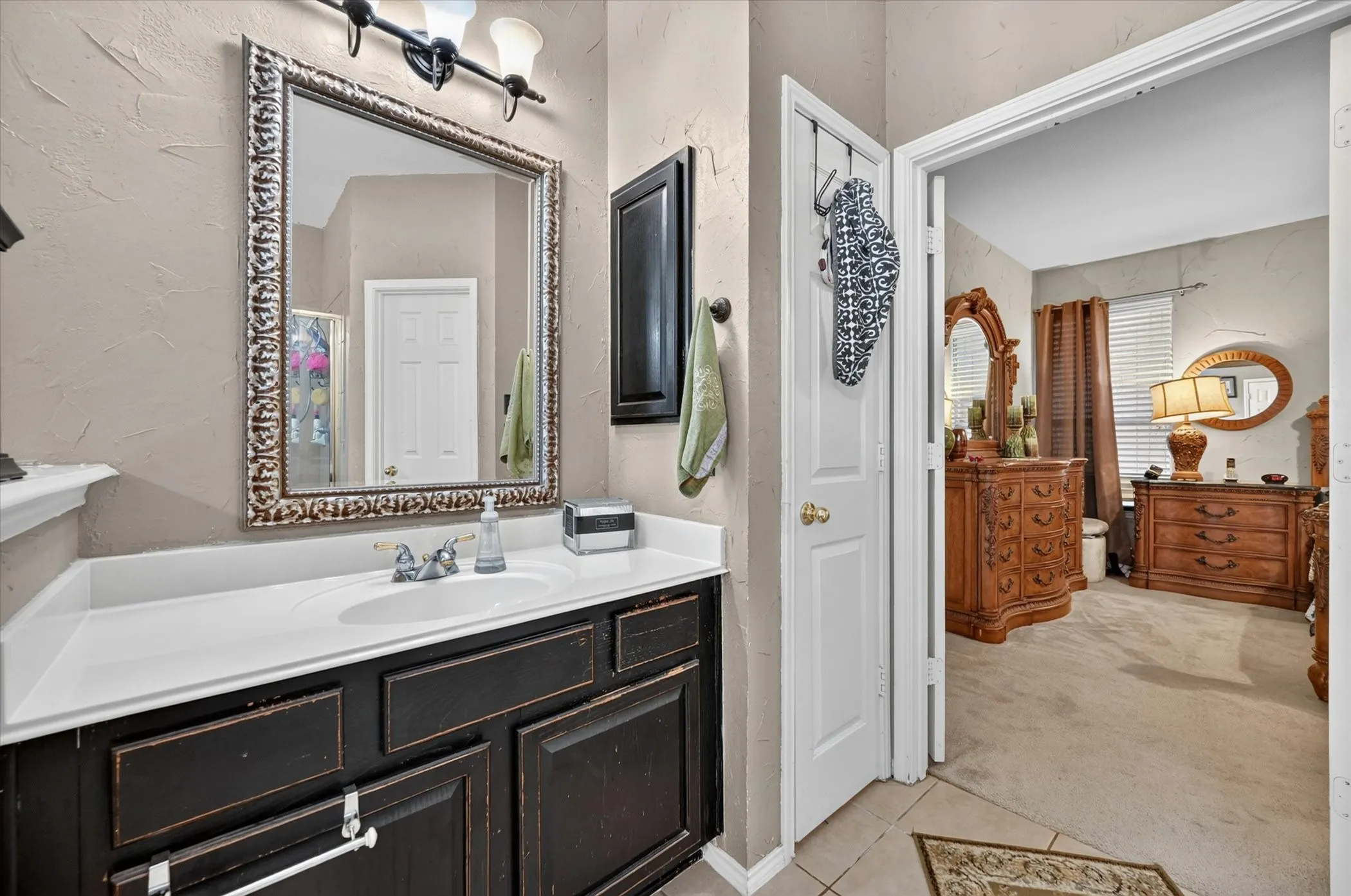 Bathroom featuring a dark wood vanity with a white countertop and integrated sink, framed mirror, and wall-mounted light fixture