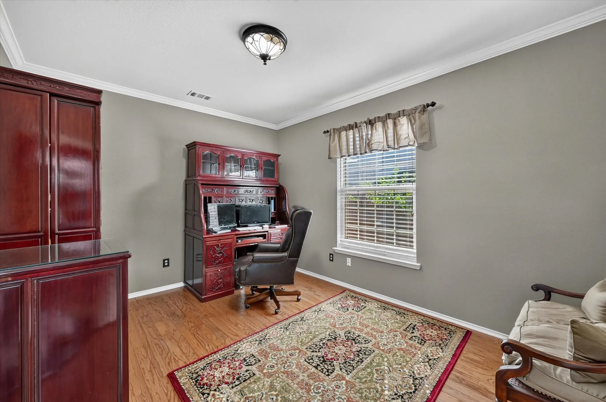 Spacious room featuring wood-finish flooring, a single window with blinds, and neutral wall paint