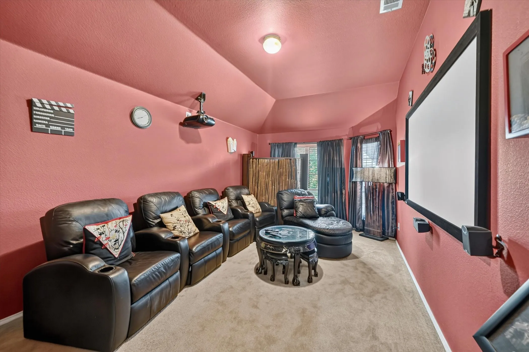 Dedicated media room featuring a large projection screen, mounted projector, and sloped ceiling