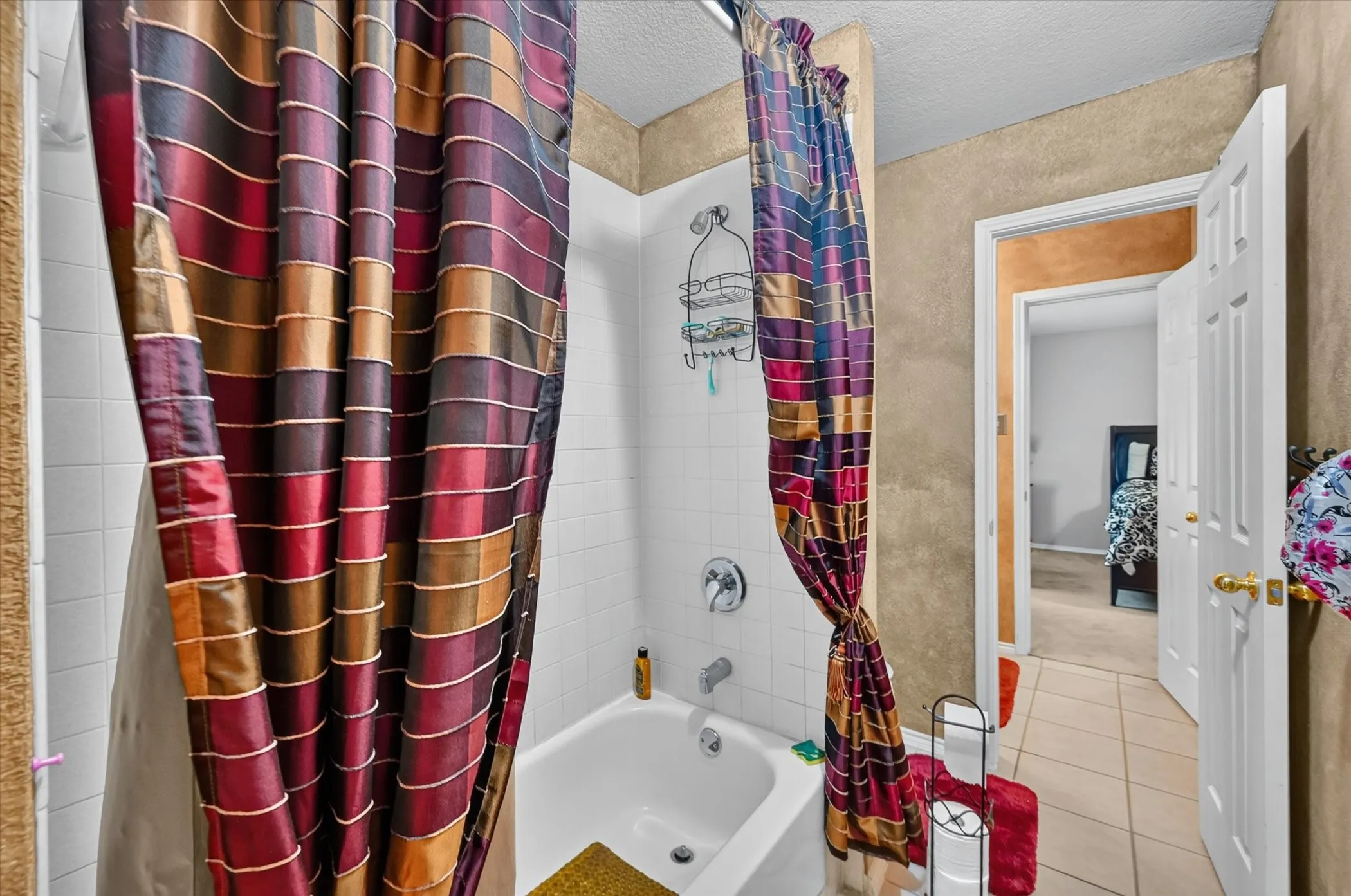 Full bath featuring a white tub, chrome fixtures, and white tiled shower surround