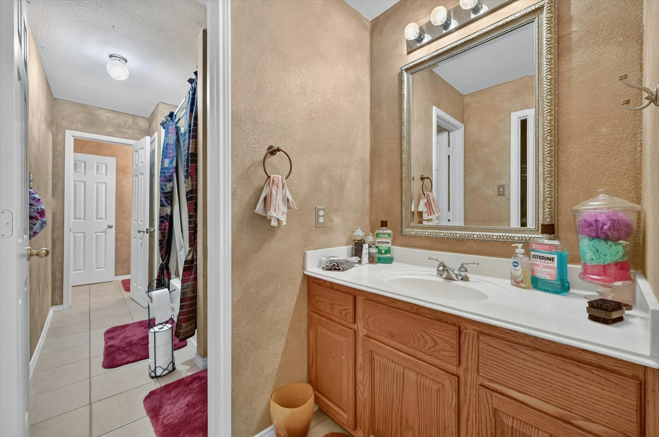 Bathroom vanity featuring a single basin sink, laminate countertop, and wood-finish cabinetry