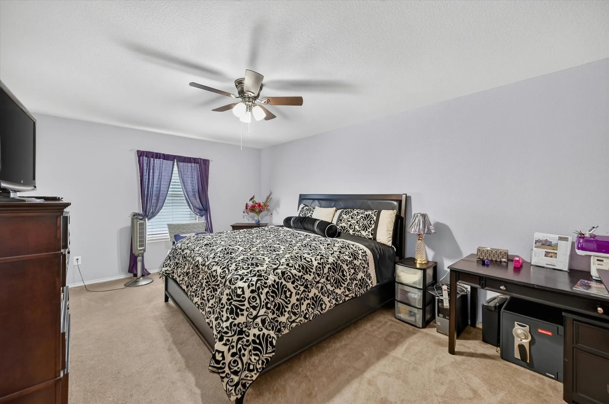 Carpeted interior room featuring a ceiling fan, window with blinds, and light-toned walls