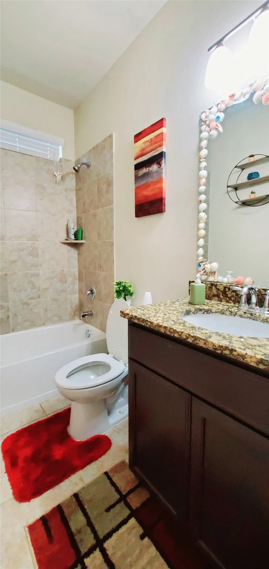 Bathroom featuring a tub/shower combination with tile surround, a dark wood-finish vanity with a granite-style countertop, and a single basin sink