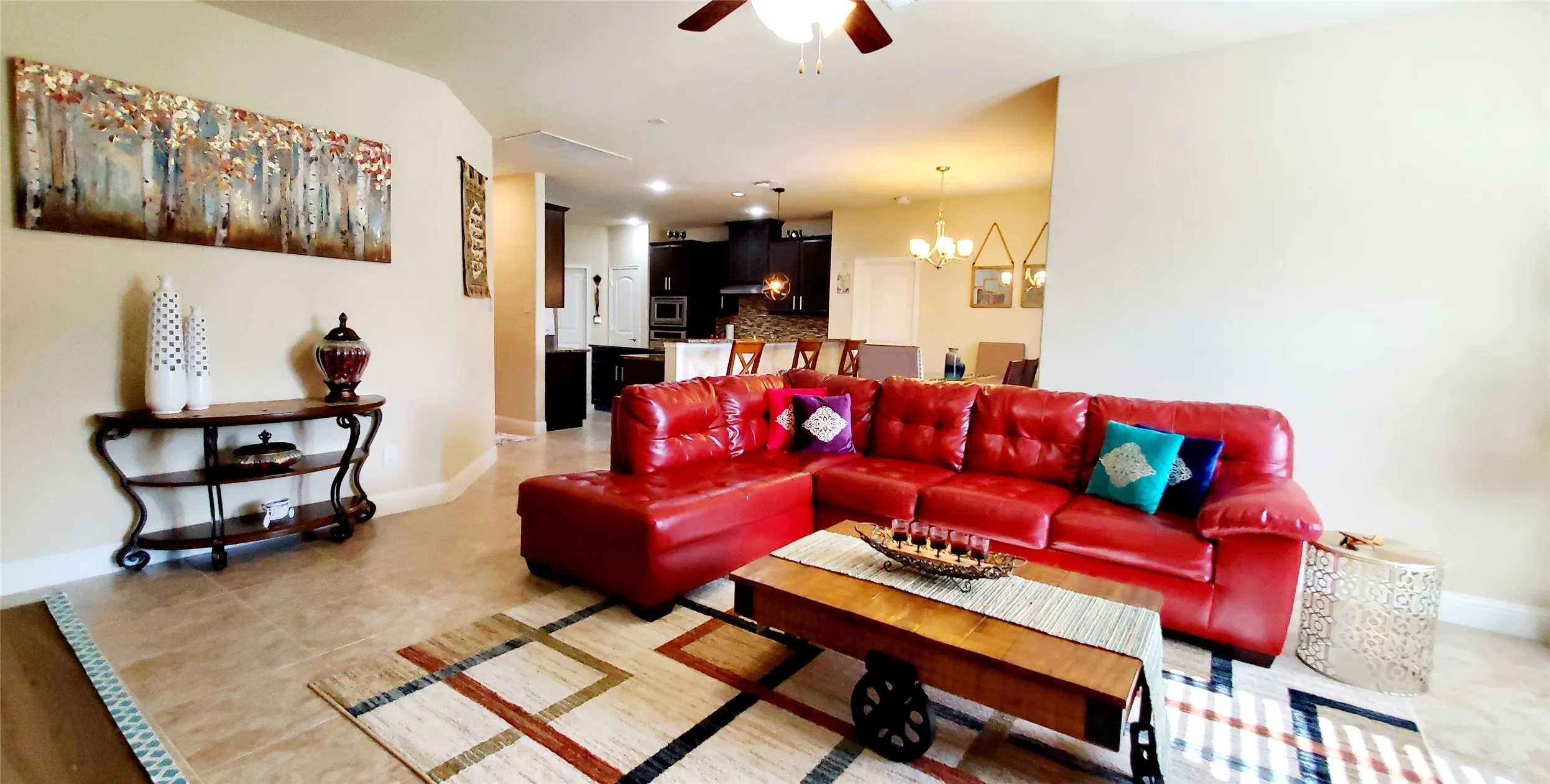 Open-concept living area featuring light-toned tile flooring, recessed lighting, and a ceiling fan