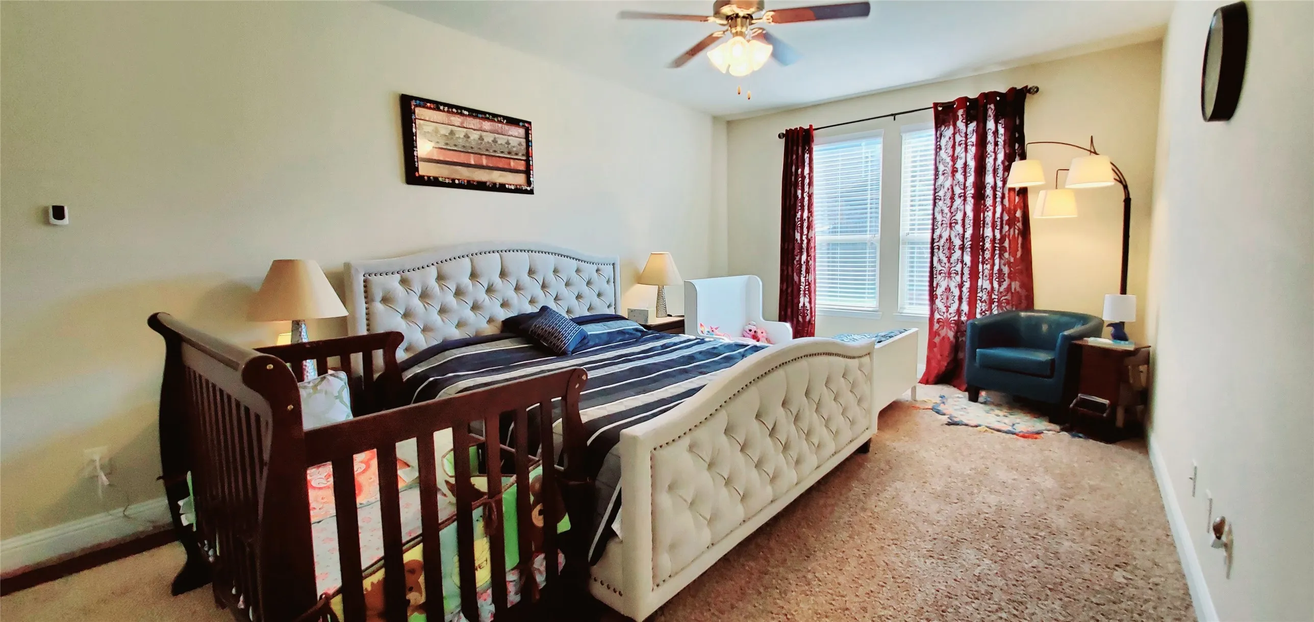 Spacious room featuring carpeting, a ceiling fan with light fixture, and windows with blinds
