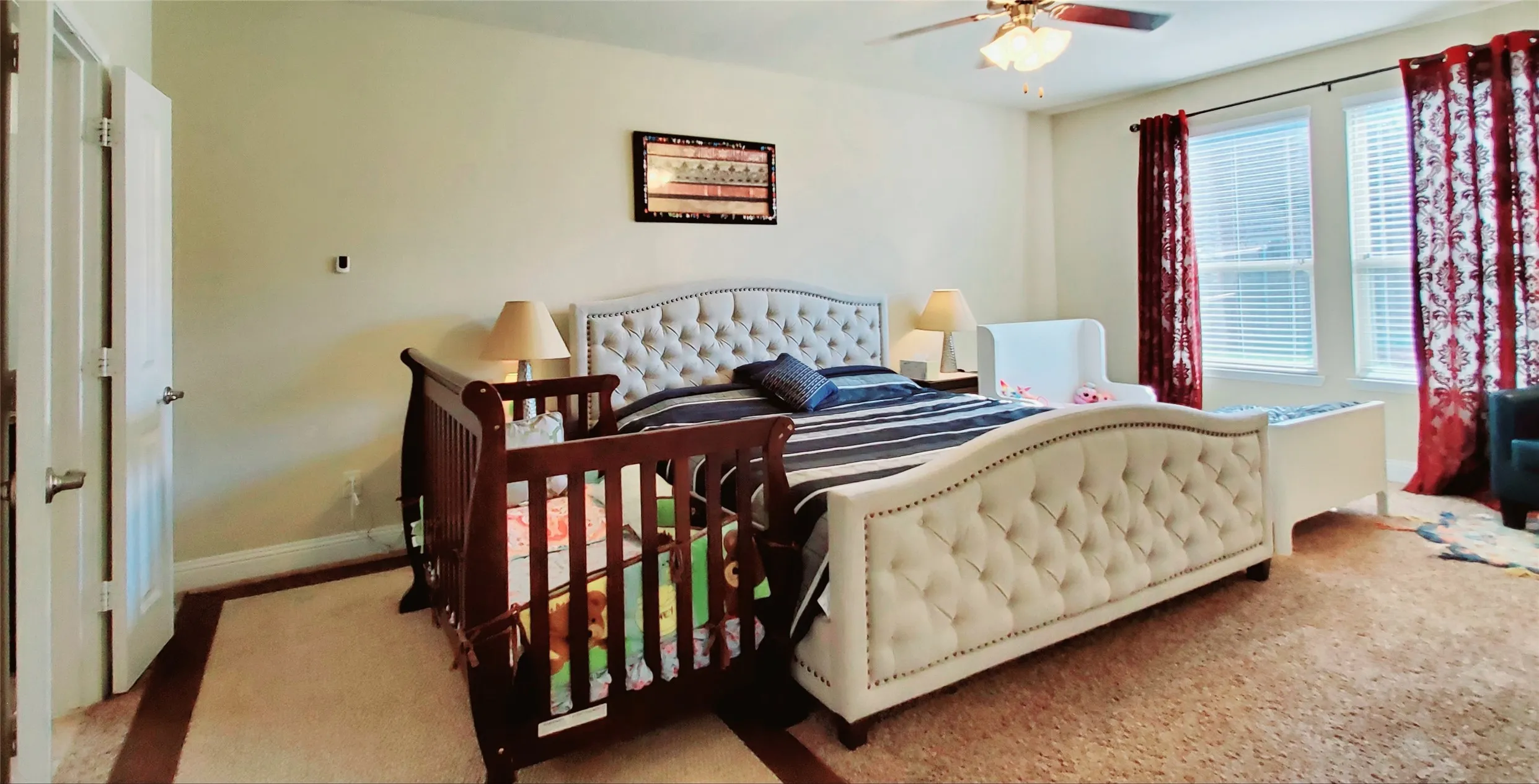 Bright room featuring multiple windows, a ceiling fan with integrated lighting, two-panel interior doors, and a combination of wall-to-wall carpeting with wood-finish flooring