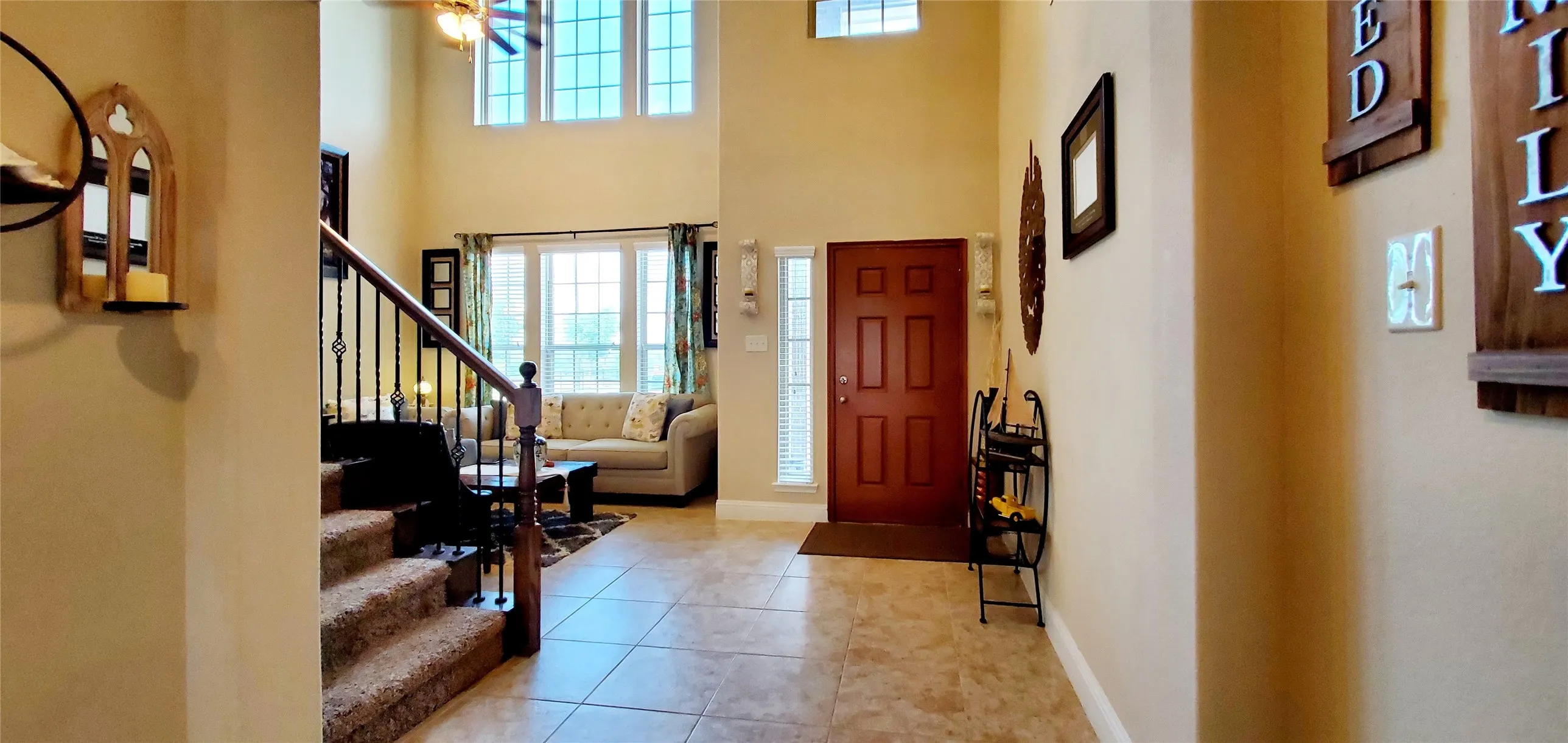 Two-story foyer featuring tile flooring, a dark wood entry door with a sidelight, and a staircase with dark wood newel posts and wrought iron balusters