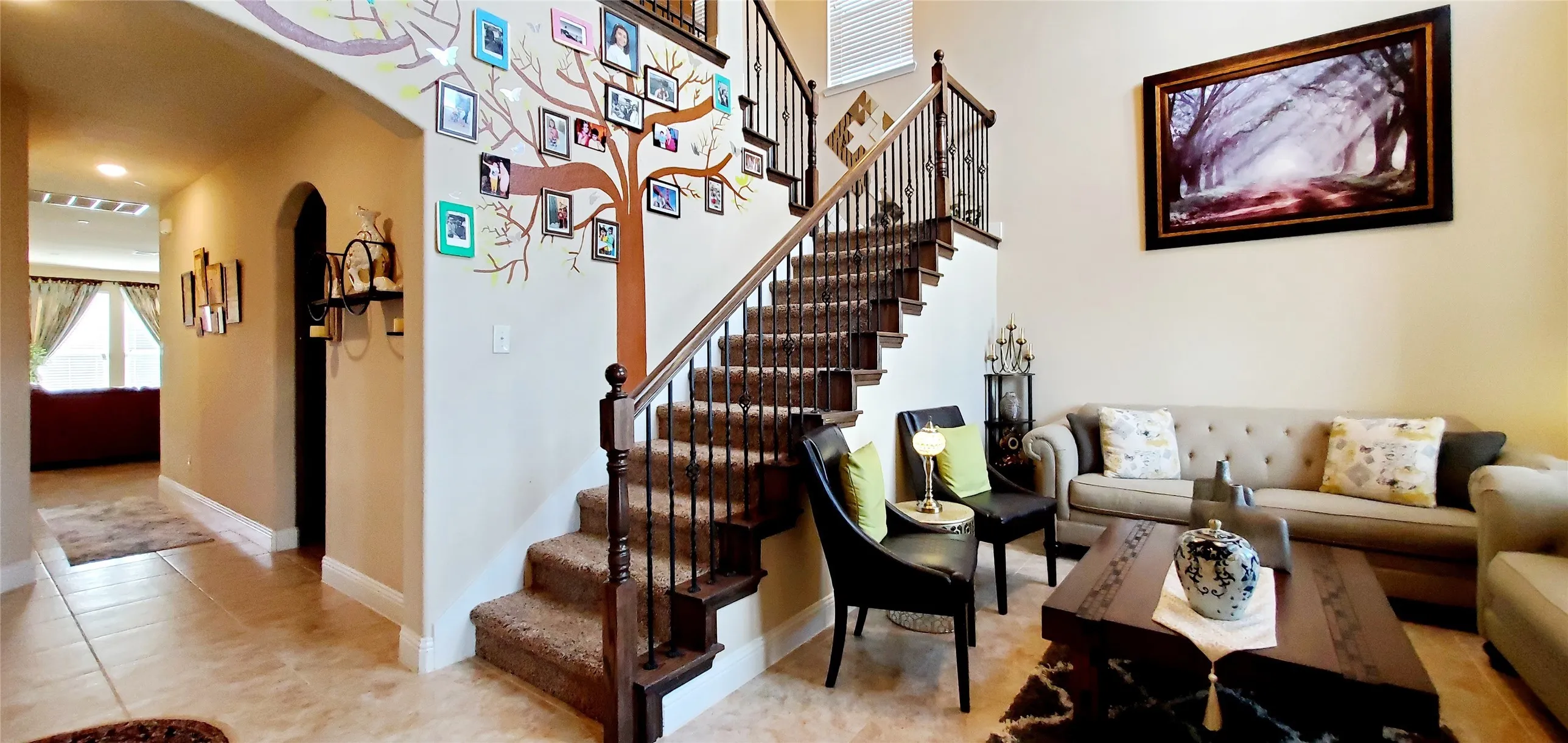 Grandiose two-story entry with a carpeted staircase featuring wrought iron balusters and a dark wood handrail