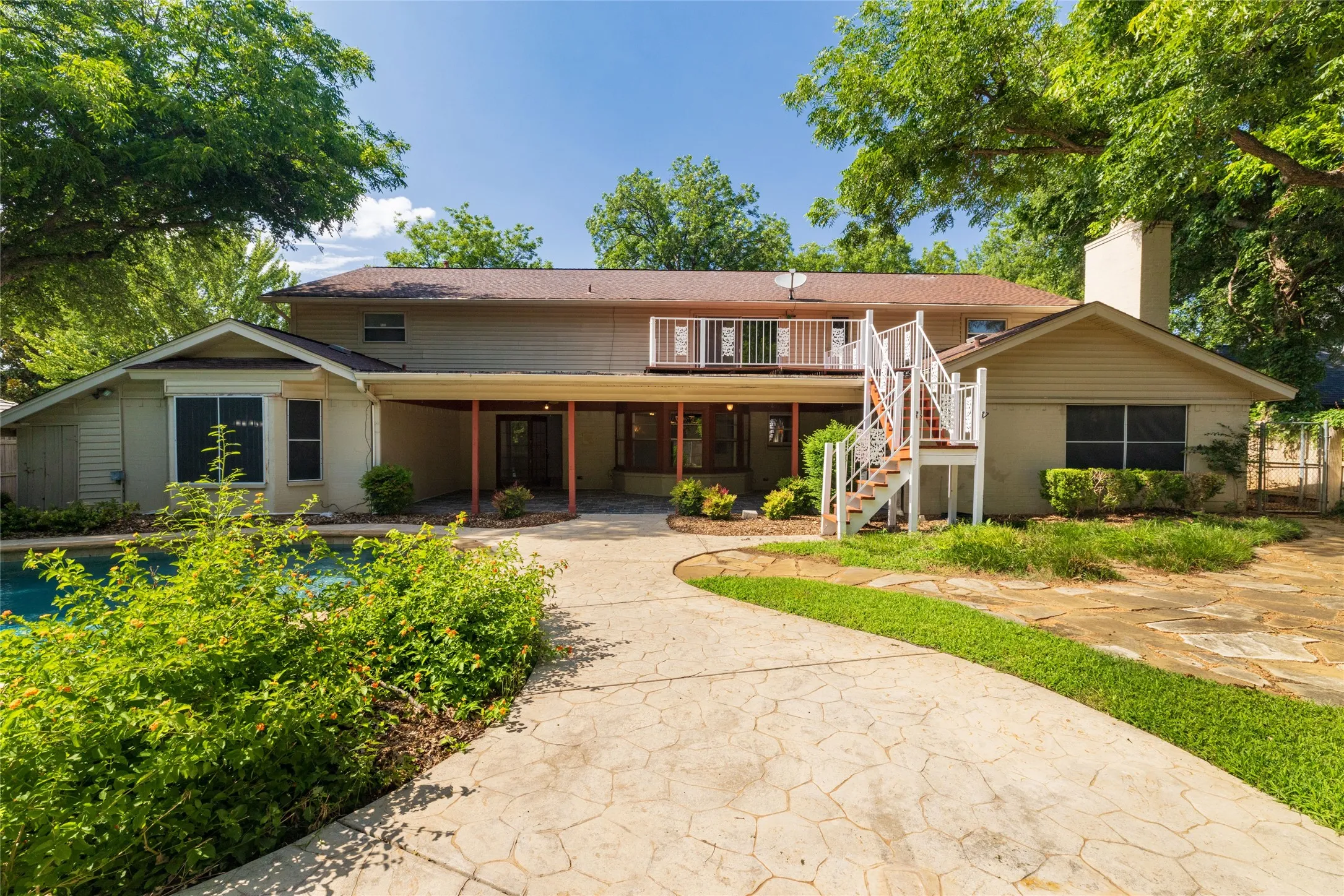 Landscaped backyard looking at back of home with upstairs balcony and covered back porch with outdoor staircase to the upstairs back balcony, with a flagstone outdoor BBQ area 59.4 x 30.10