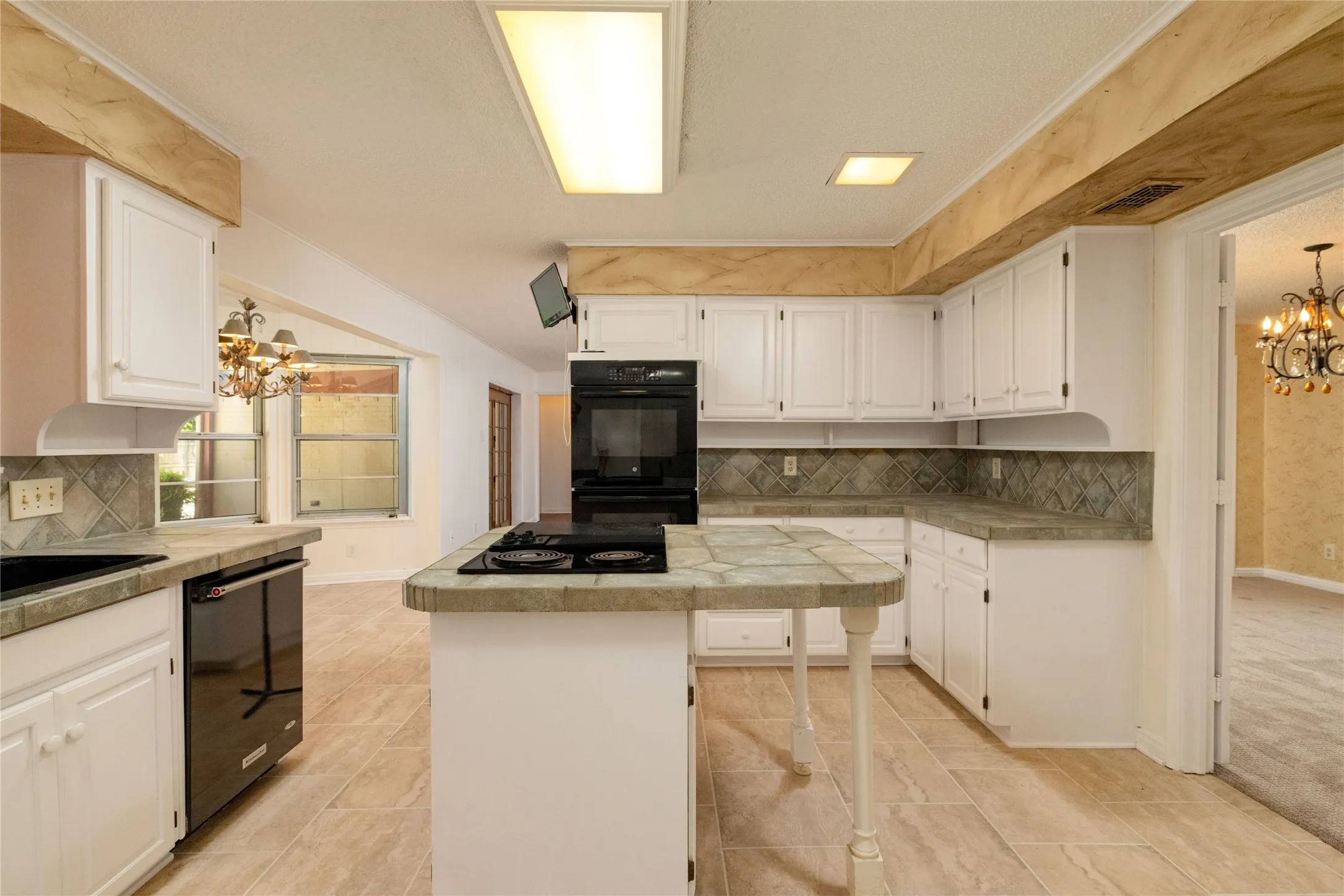 13.3 x 13.3 Kitchen featuring white cabinetry, tile countertops, integrated black double oven, and a central island with a built-in cooktop