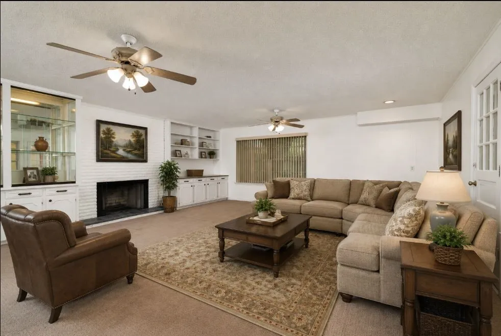 Spacious 20.5 x 20.5 living area featuring a white brick fireplace with a dark hearth, built-in cabinetry, and ceiling fans
