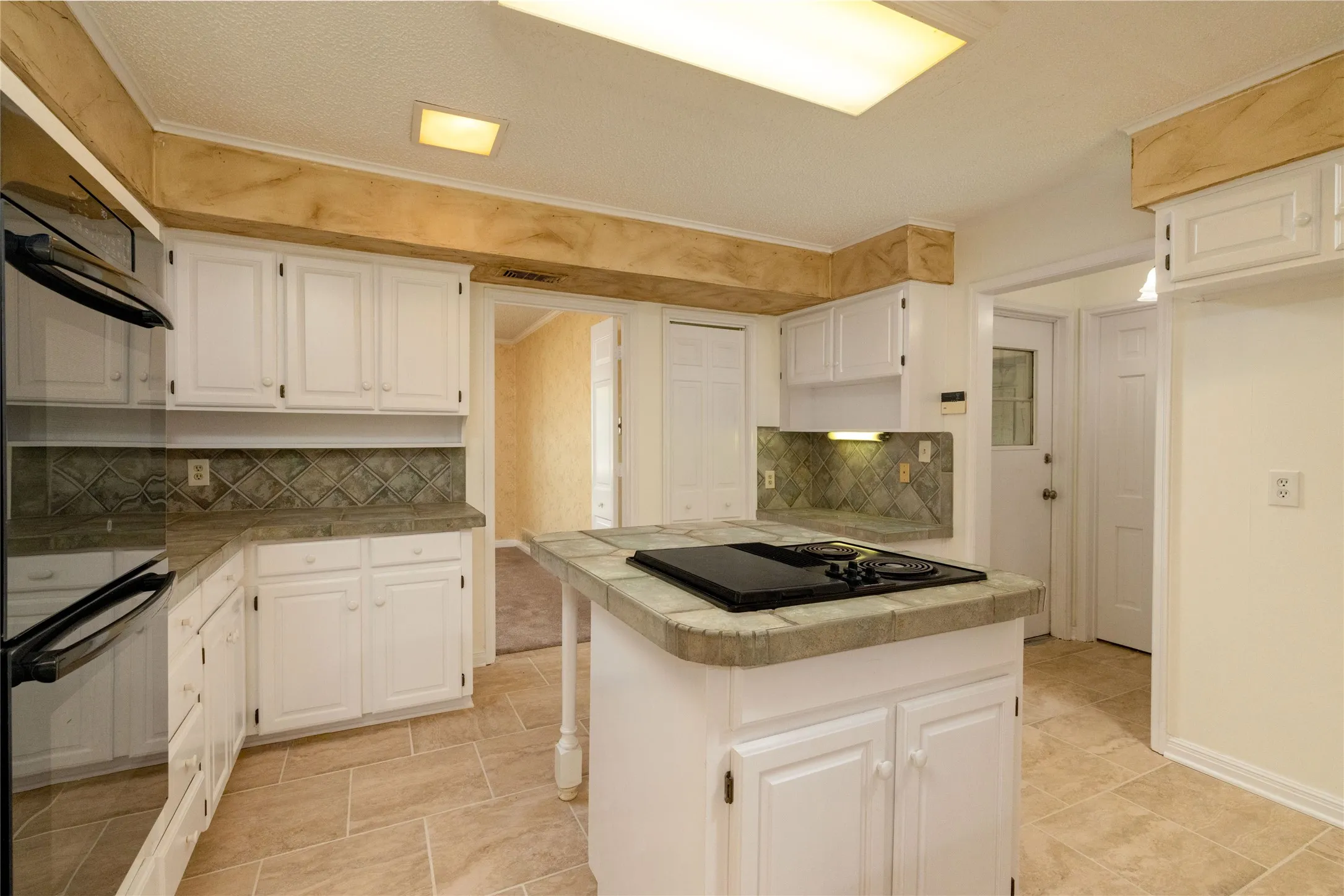 13.3 x 13.3 Kitchen featuring white cabinetry, tile countertops, tile backsplash, built-in cooktop island, Double Ovens and new tile flooring