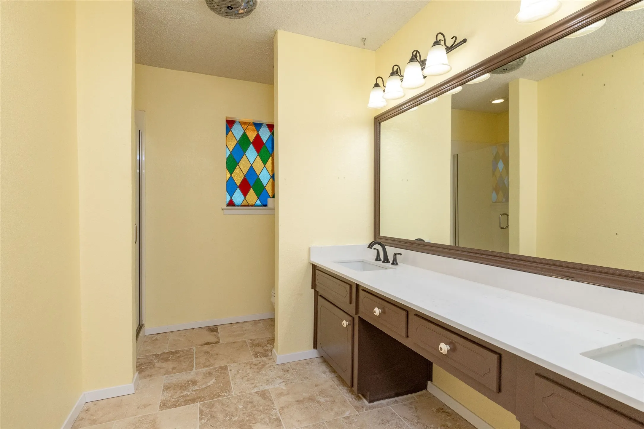 Upstairs Dual vanity 10.10 x 9.1 bath with walk in shower, also with white countertops, dark wood cabinetry, and oil-rubbed bronze fixtures