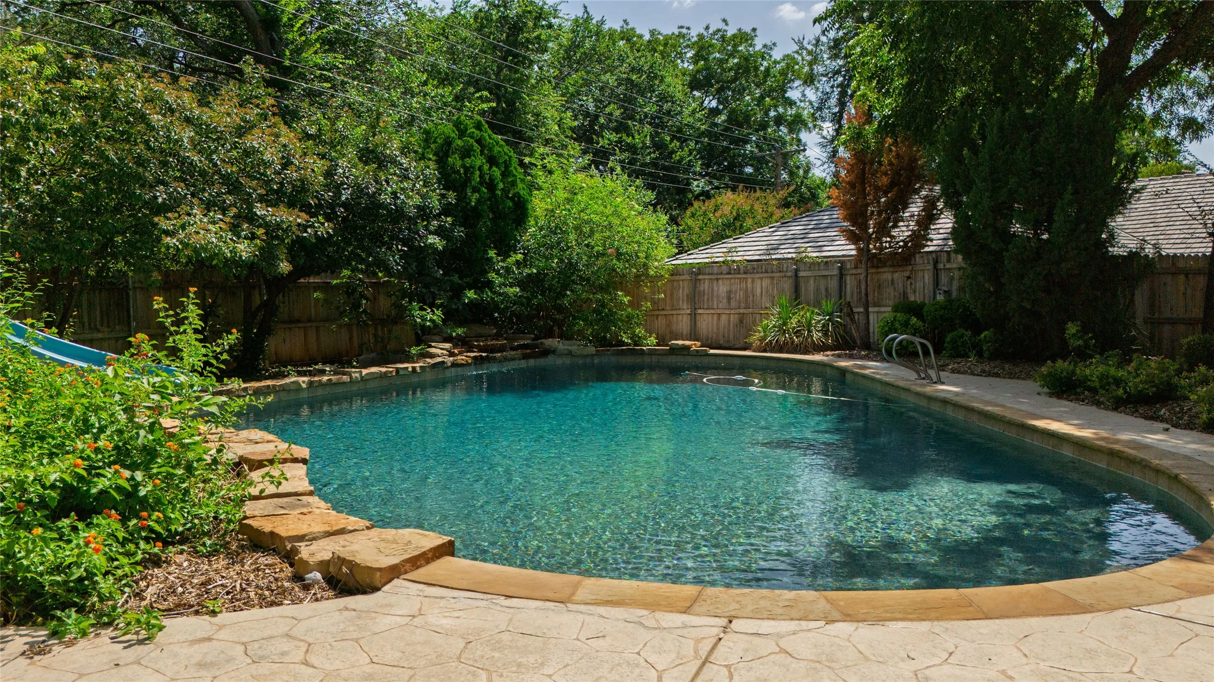 In-ground swimming pool with flagstone coping and integrated steps and waterfall