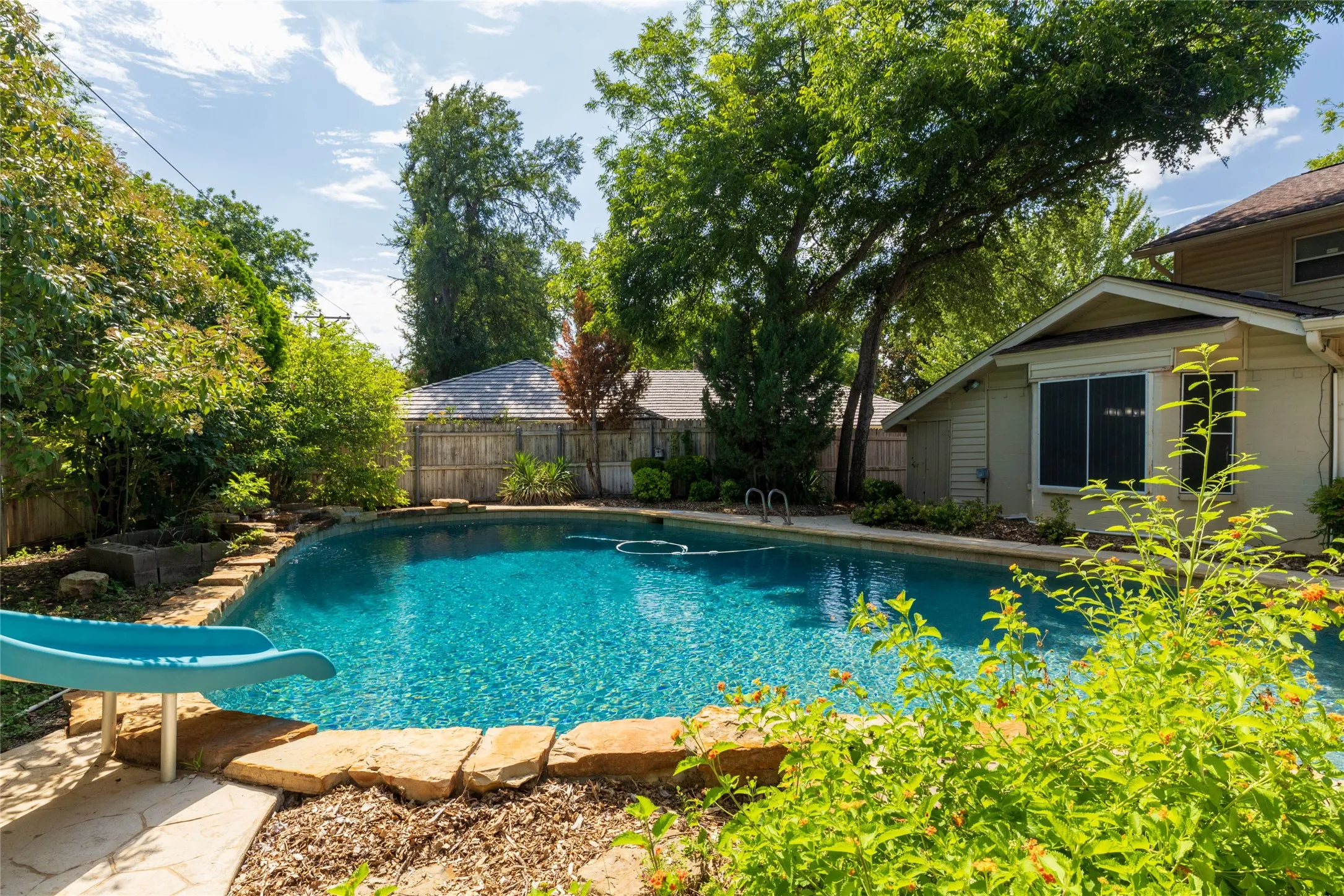 41.8 x 24.2 Outdoor swimming pool featuring a curved design and stone coping, slide and diving rock