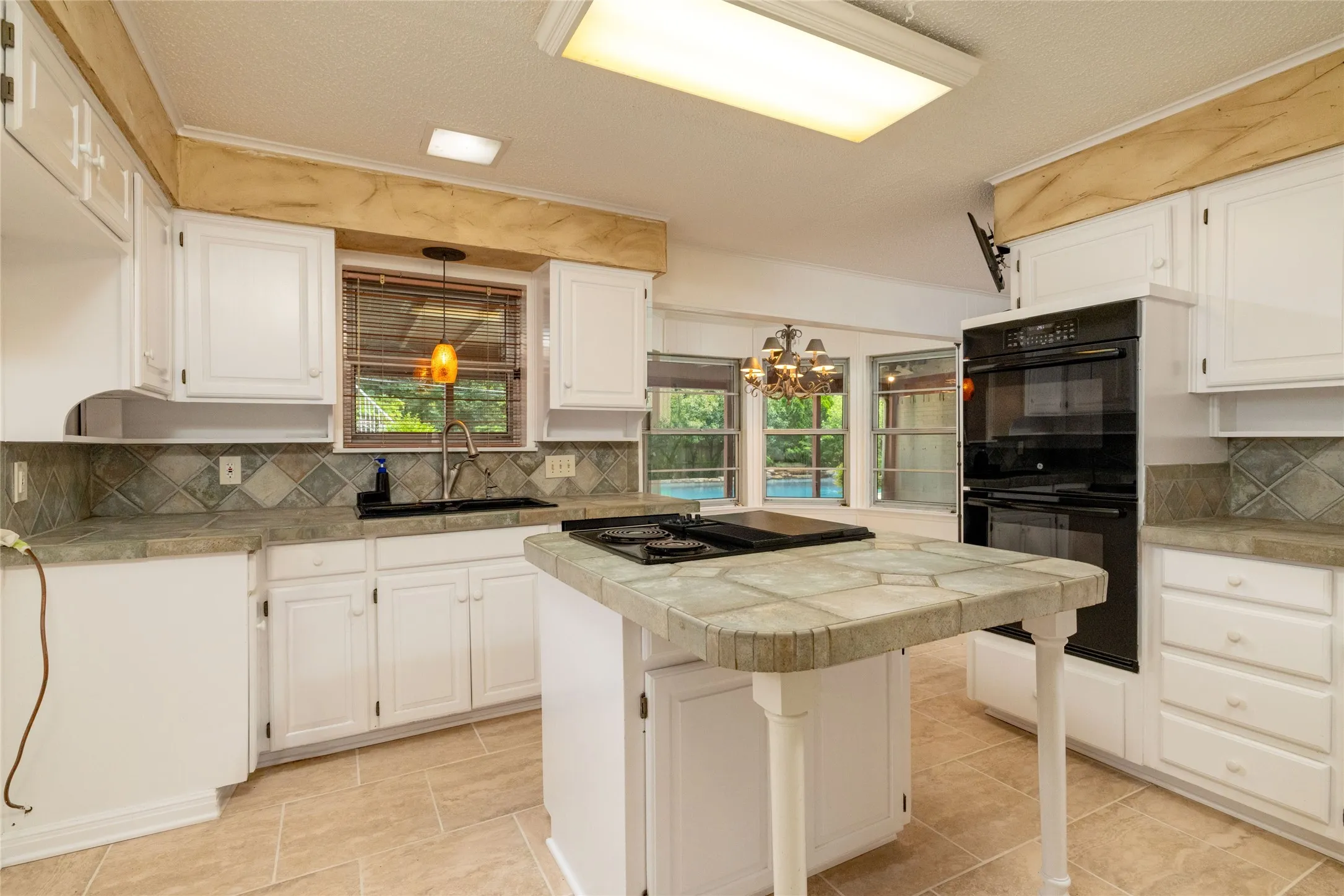 13.3 x 13.3 Kitchen featuring a central island with a tiled countertop, white cabinetry, and dual built-in ovens