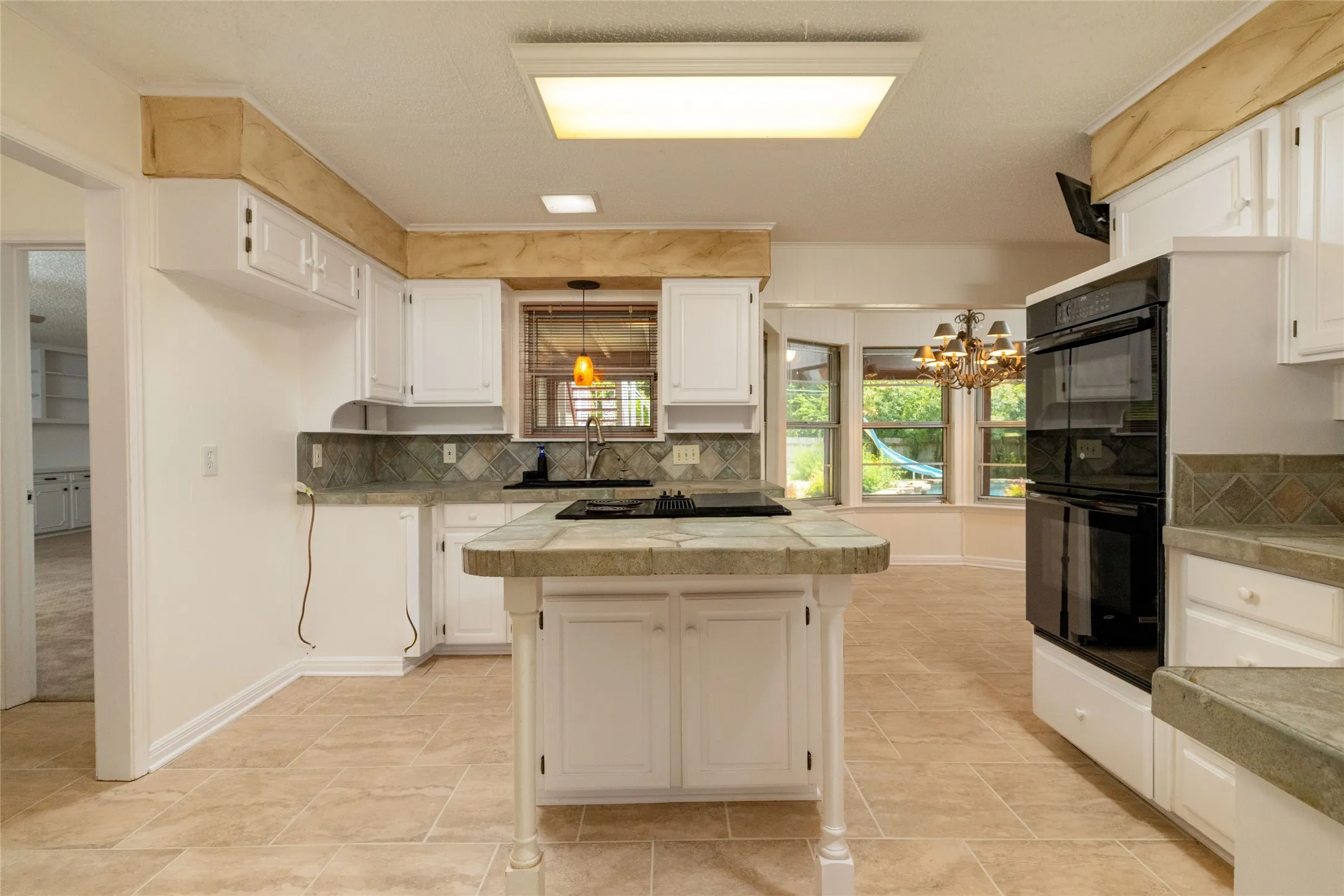 13.3 x 13.3 Kitchen featuring white cabinetry, tile countertops, double ovens, a huge amount of cabinet space and a large pantry and a full New Orleans style tile backsplash