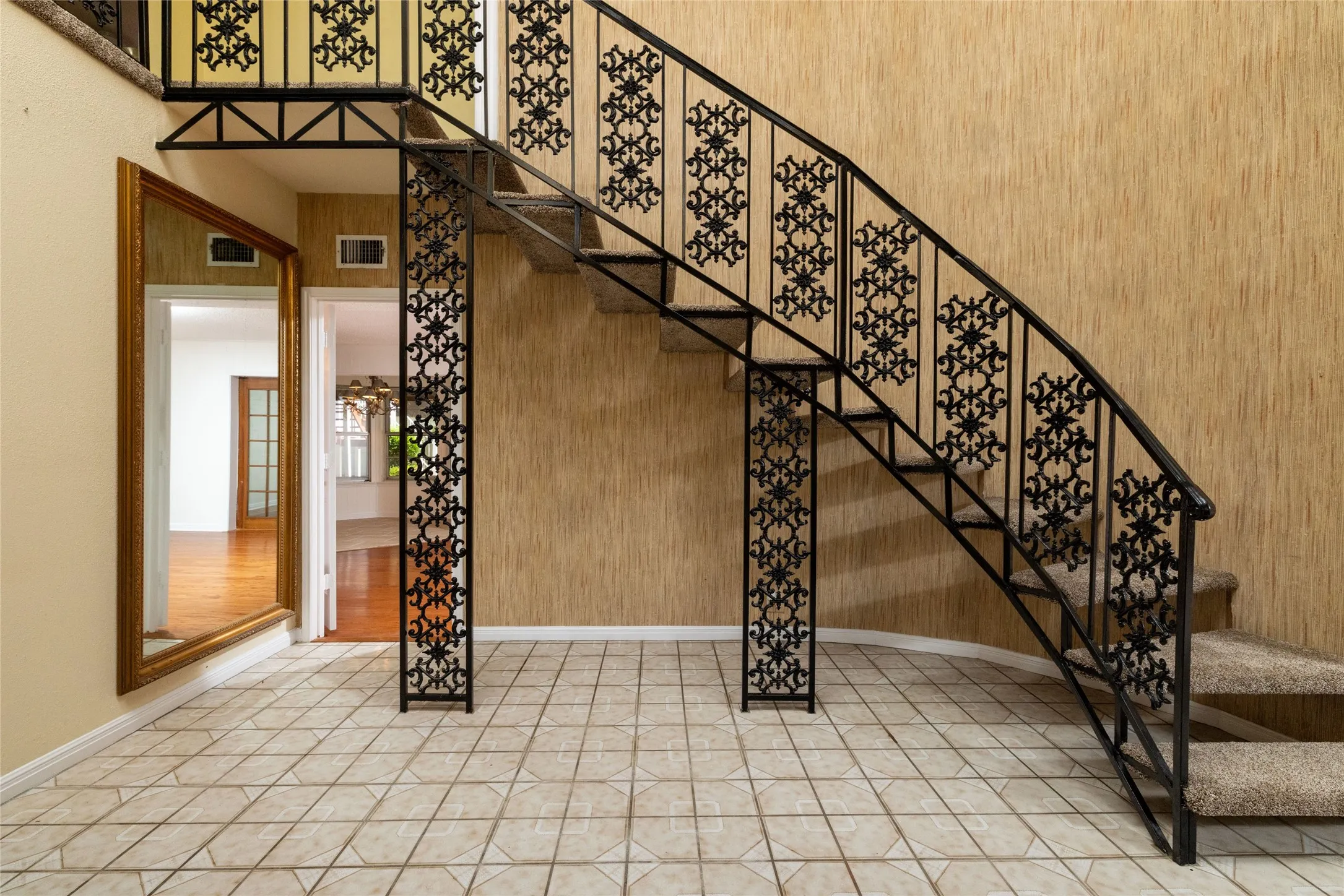 14.9 x 12 Front Foyer Curved staircase with ornate black wrought iron balusters and carpeted treads