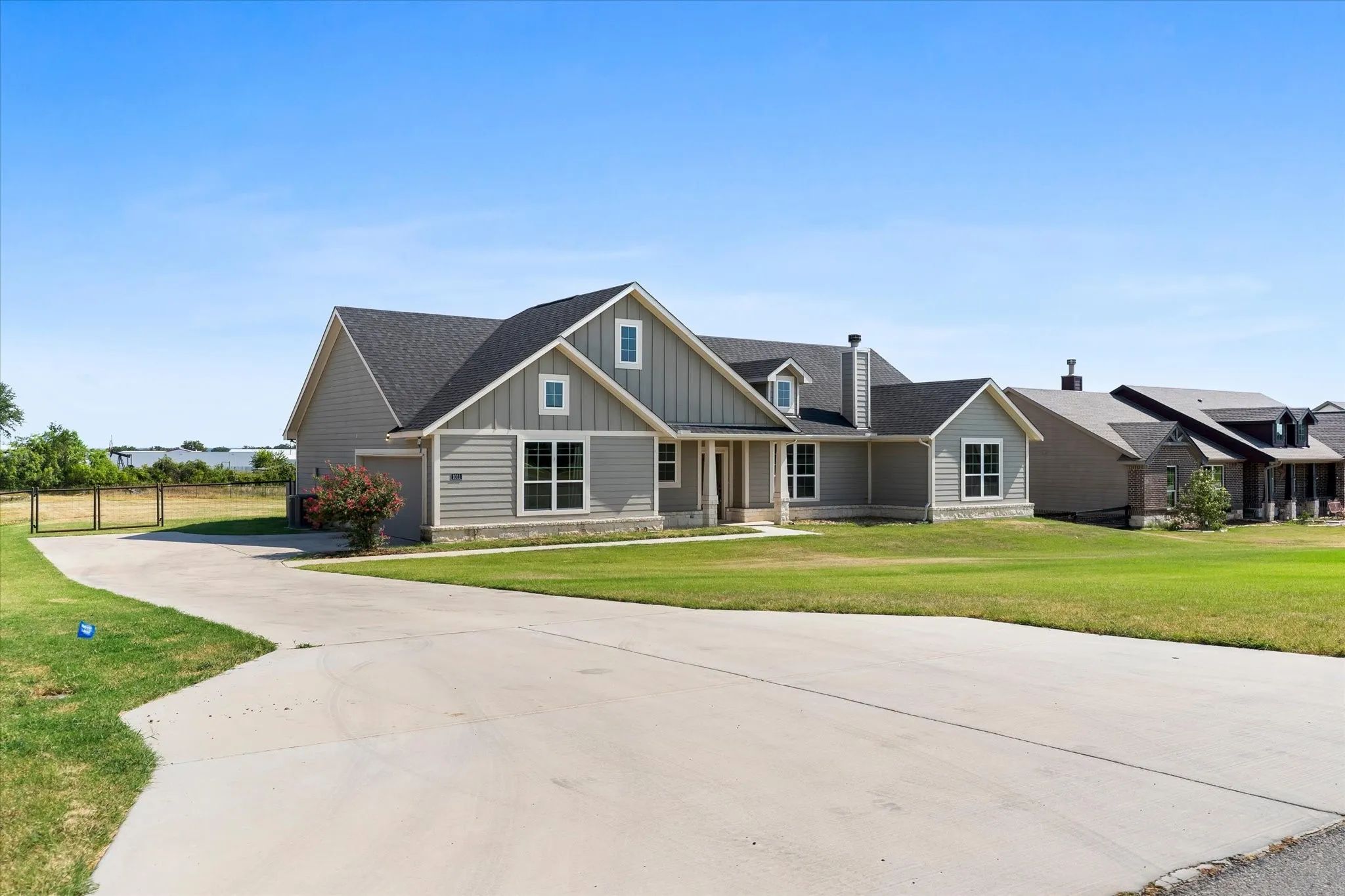 Spacious farmhouse-style residence featuring a composite exterior with vertical siding accents, multiple gabled rooflines with architectural dormers, and a concrete driveway approach