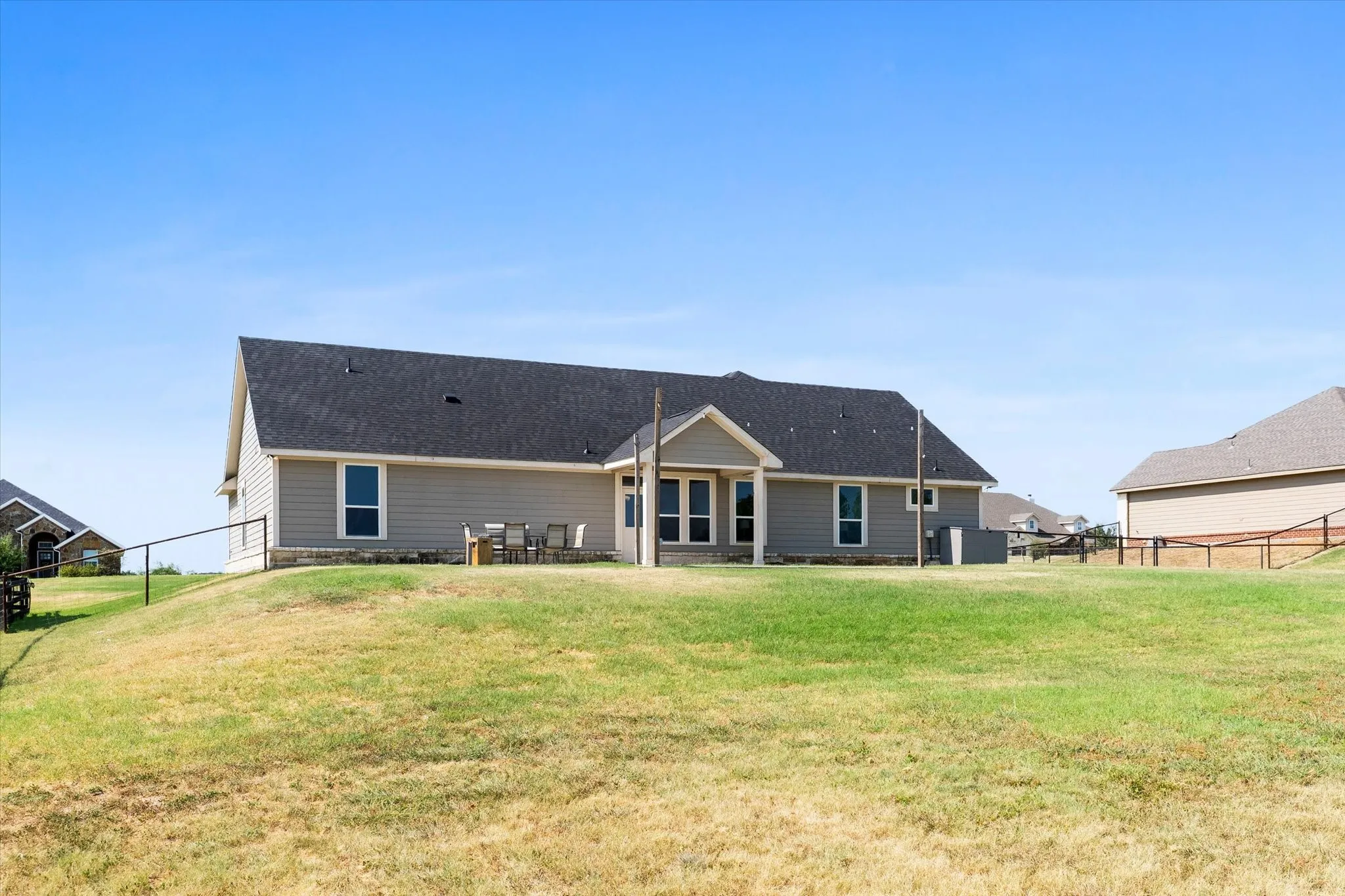 Spacious single-story residence featuring a gabled roof with architectural detailing, board-and-batten exterior siding in neutral tones, and multiple window openings throughout