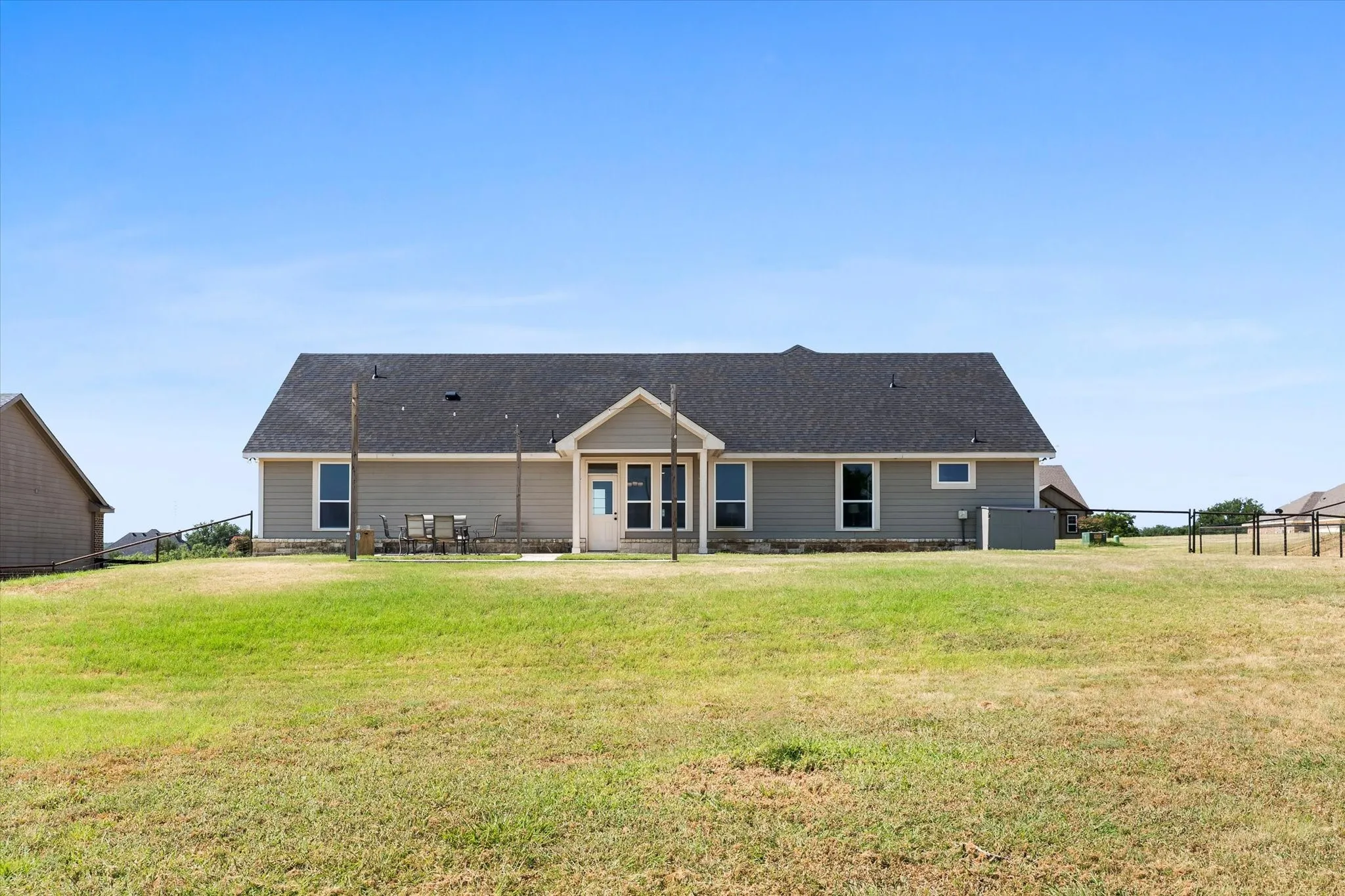 Rear exterior featuring a covered patio, multiple windows, and a dark shingle roof