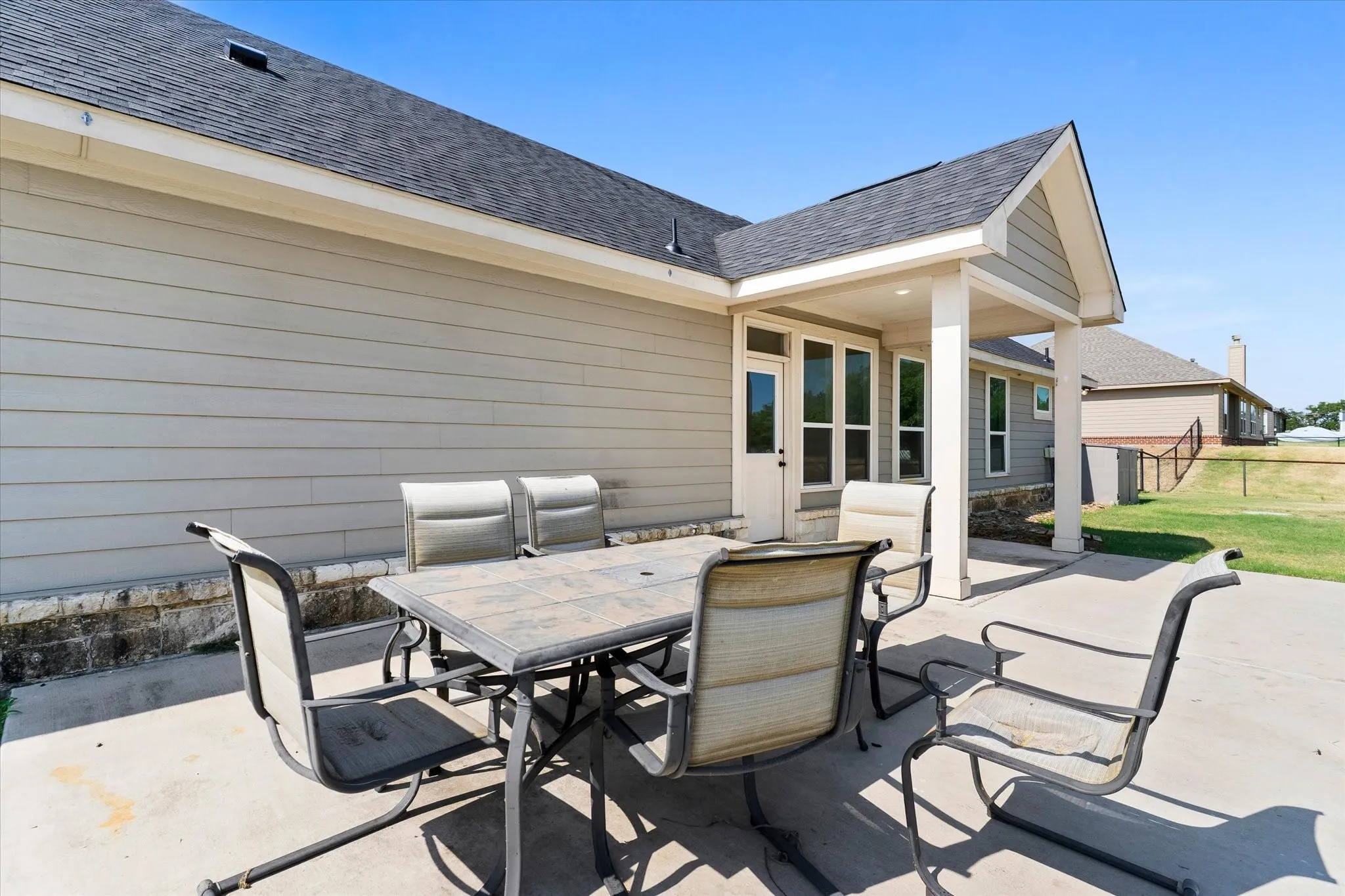 Expansive concrete patio with a covered outdoor area, featuring a gabled roofline and siding exterior