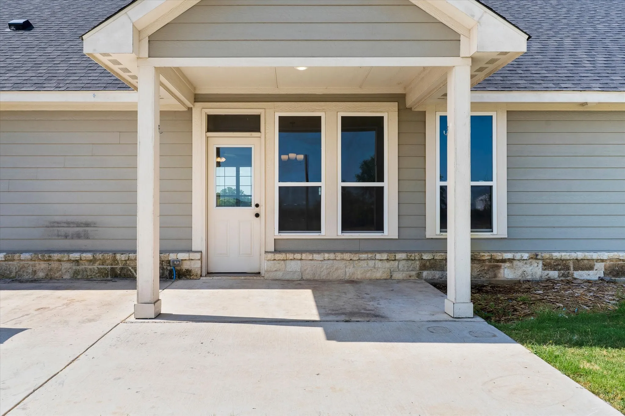 Covered entry with concrete patio, siding exterior, and stone accent foundation