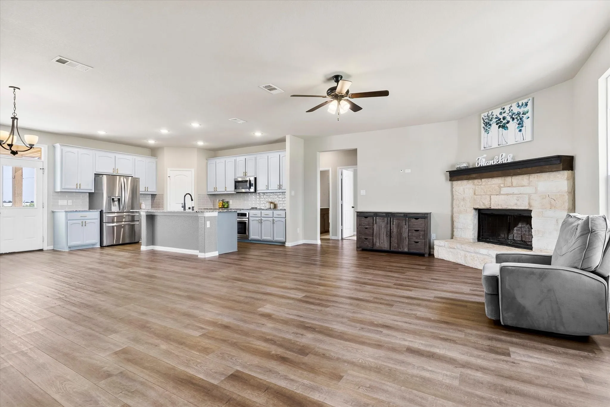 Wood-finish flooring throughout, featuring a kitchen with light-toned cabinetry, stainless steel appliances, and a central island