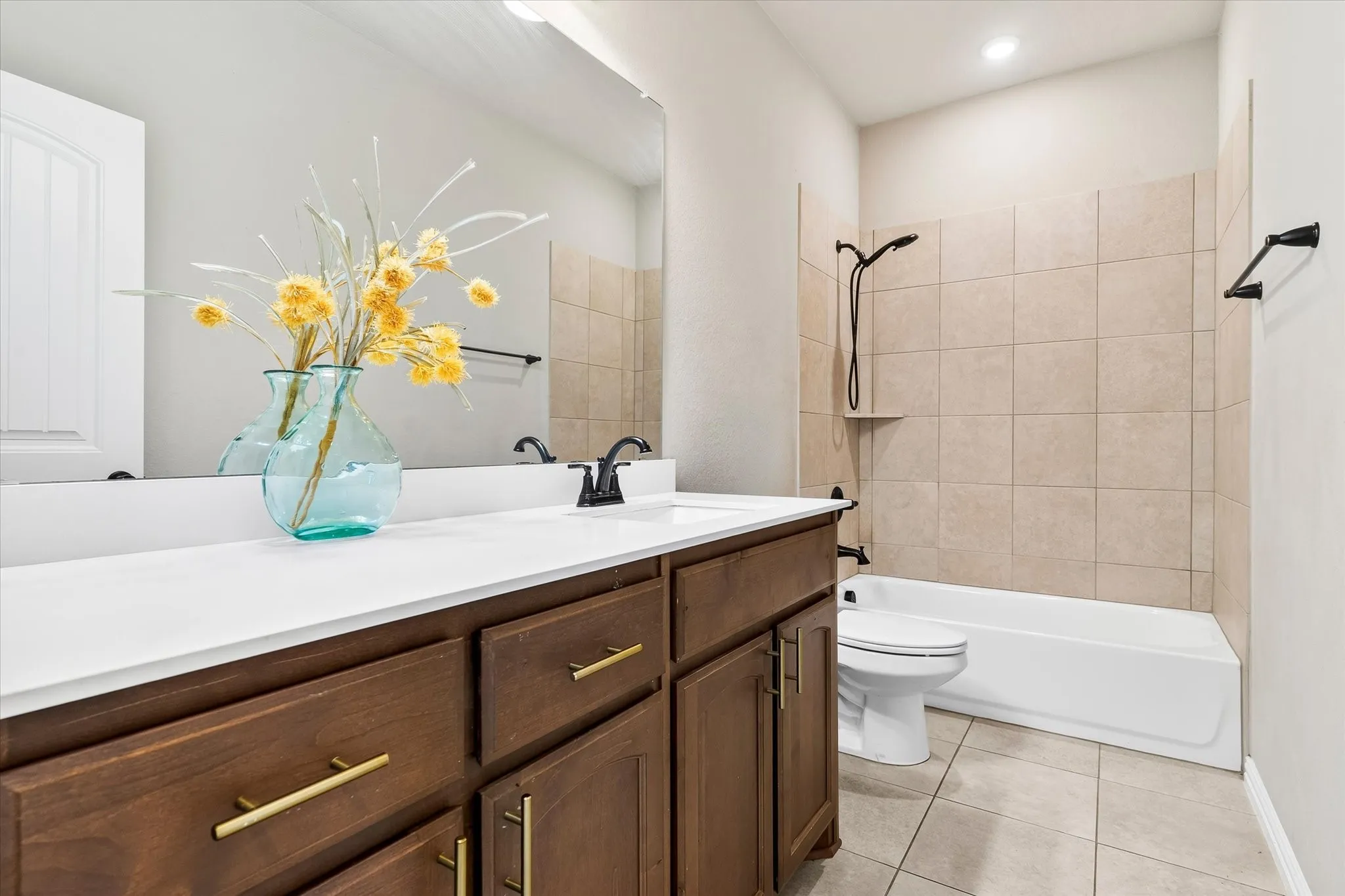 Wood-finish vanity with gold-tone hardware, white countertop, and integrated sink